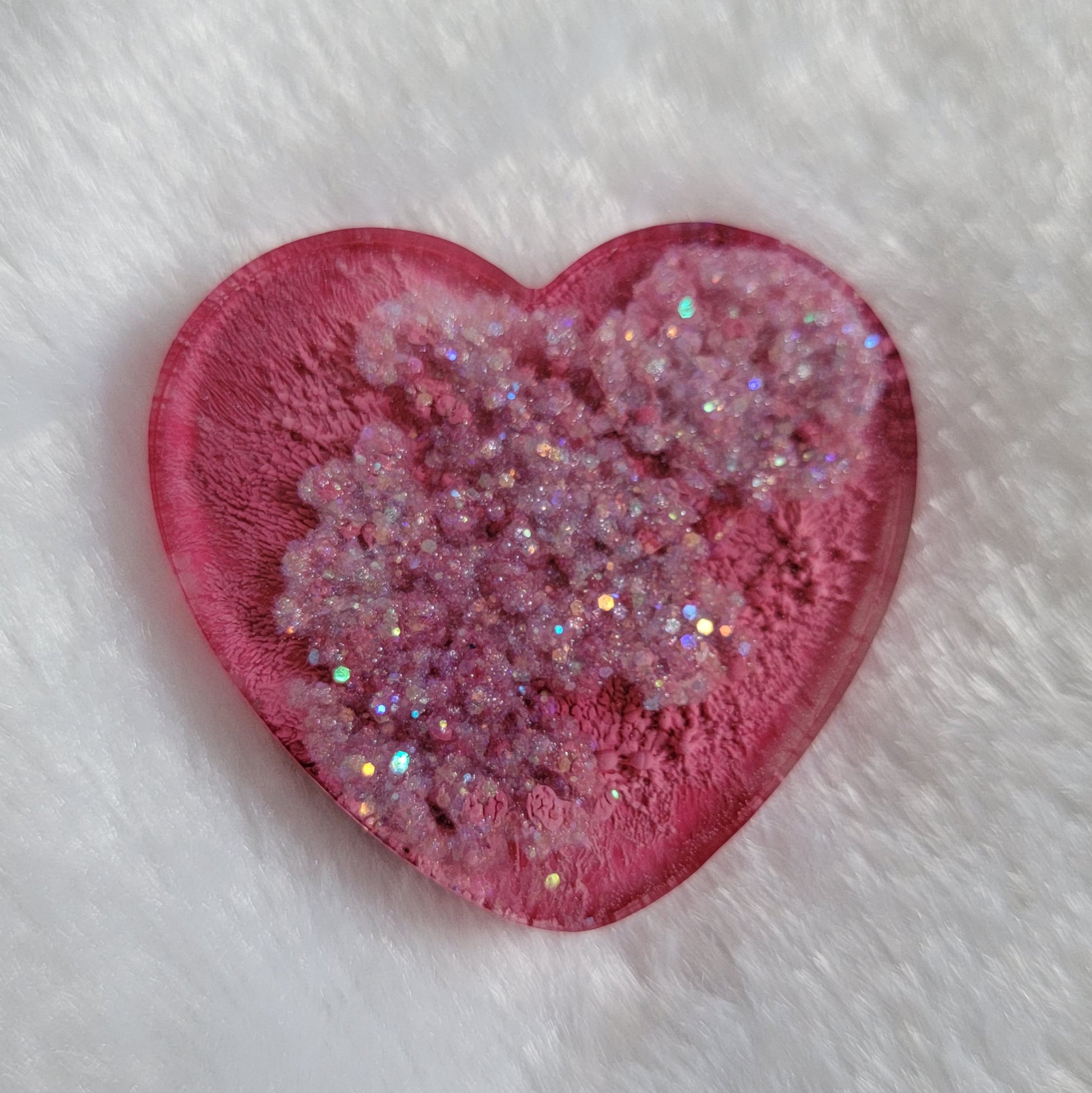 Heart shaped epoxy resin piece with dark pink ink pigment and glitter swirls.