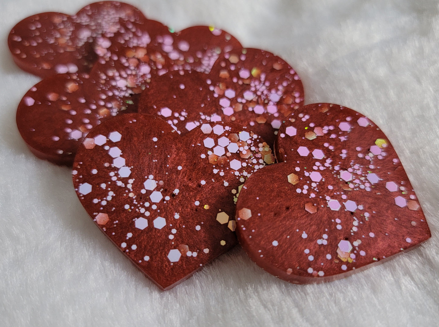 Heart shaped epoxy resin pieces, deep candy red pigment with opal white iridescent glitter.