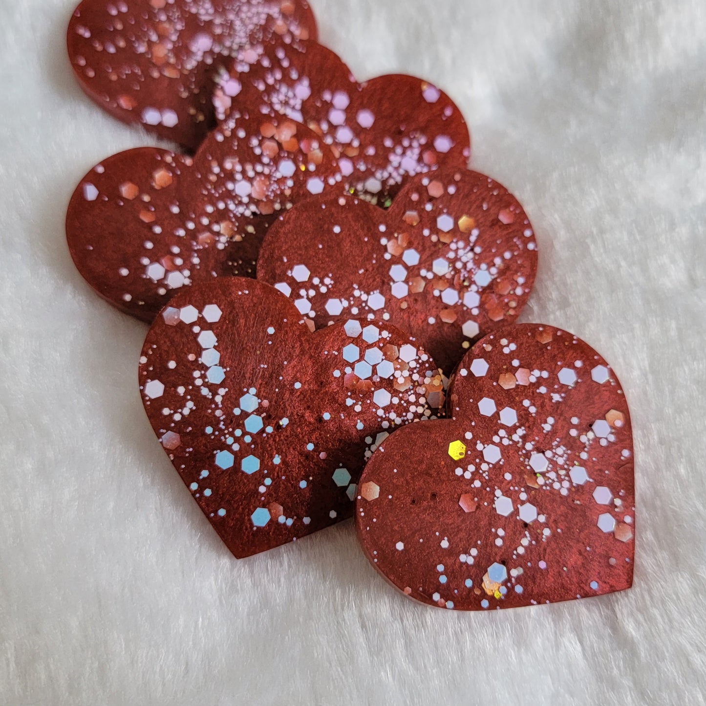 Heart shaped epoxy resin pieces, deep candy red pigment with opal white iridescent glitter.