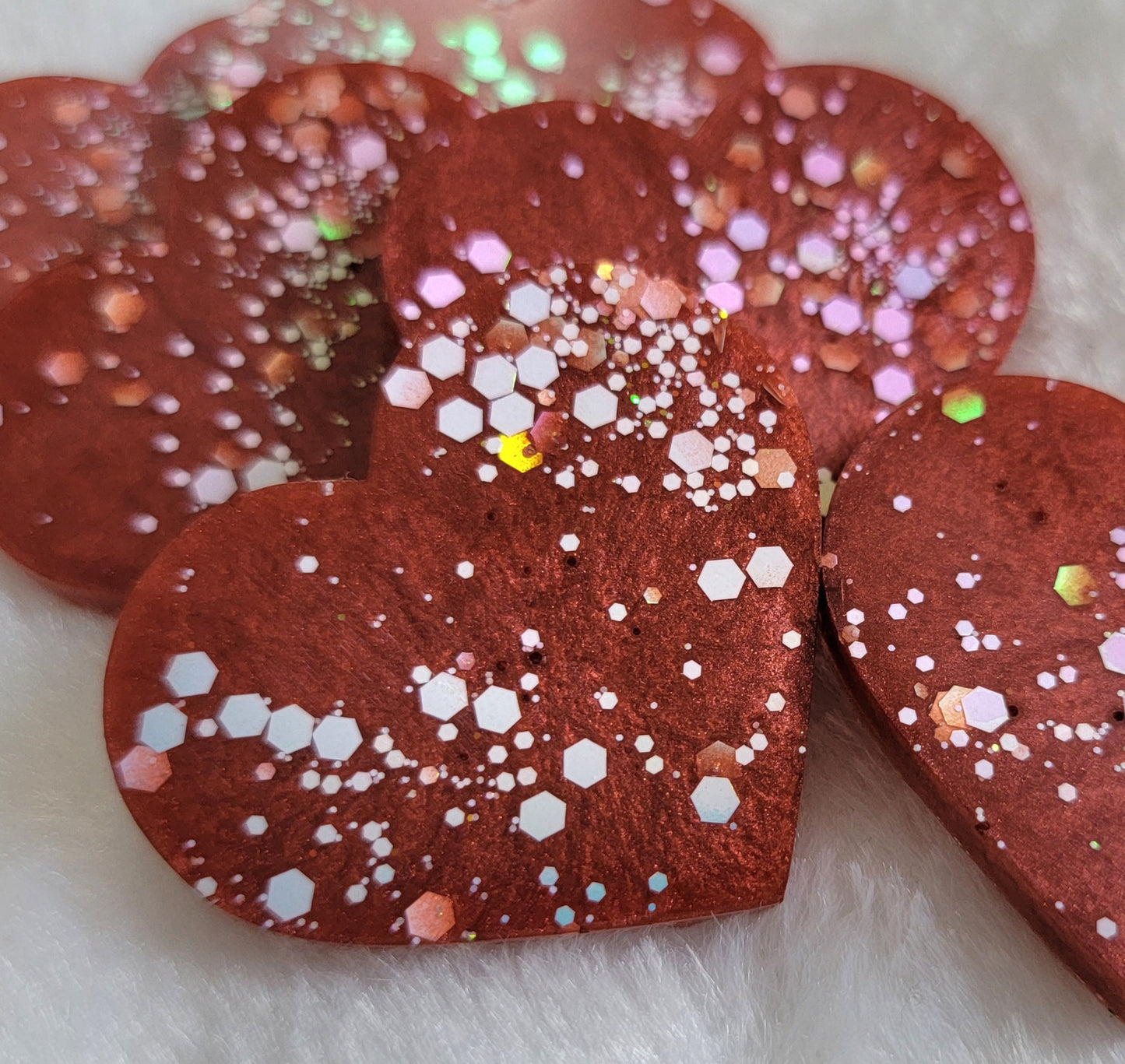 Heart shaped epoxy resin pieces, deep candy red pigment with opal white iridescent glitter.