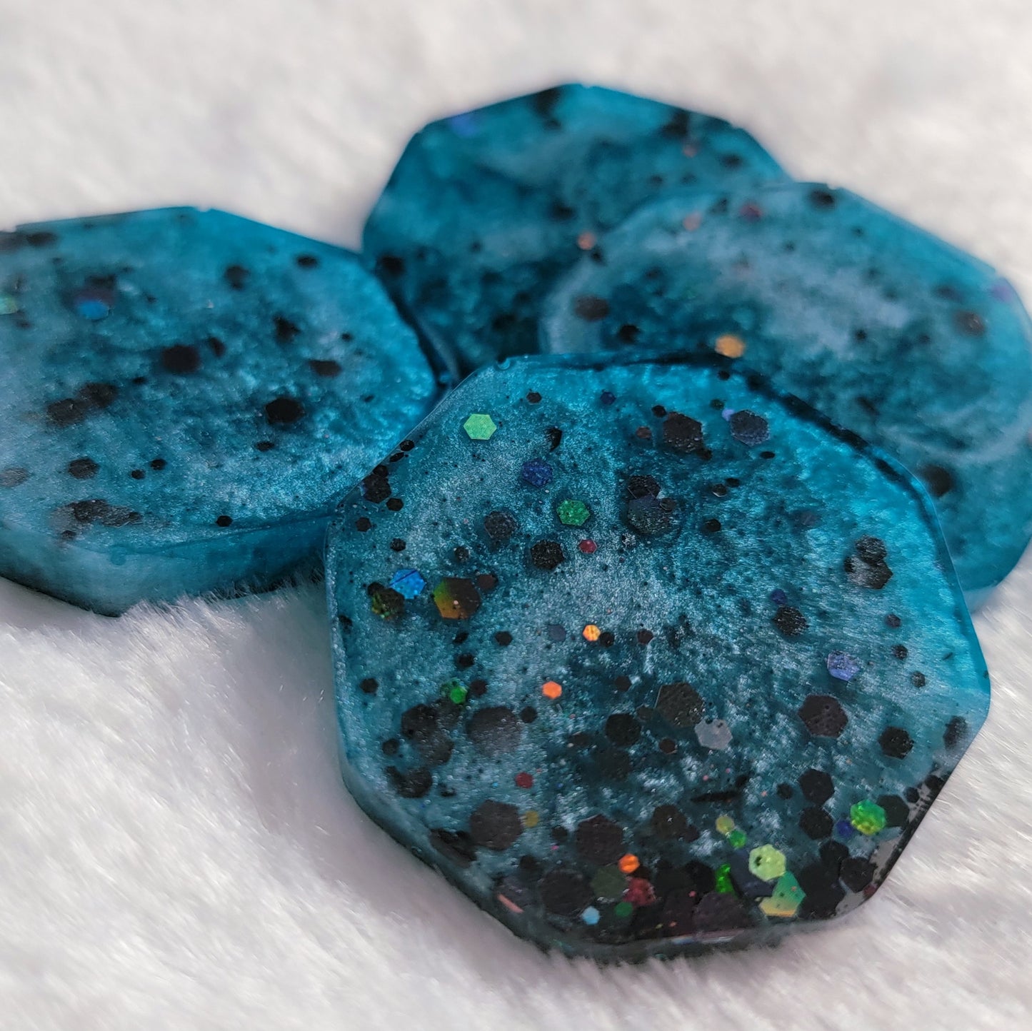 Octagon shaped epoxy resin pieces, light blue swirls with black holographic glitter.