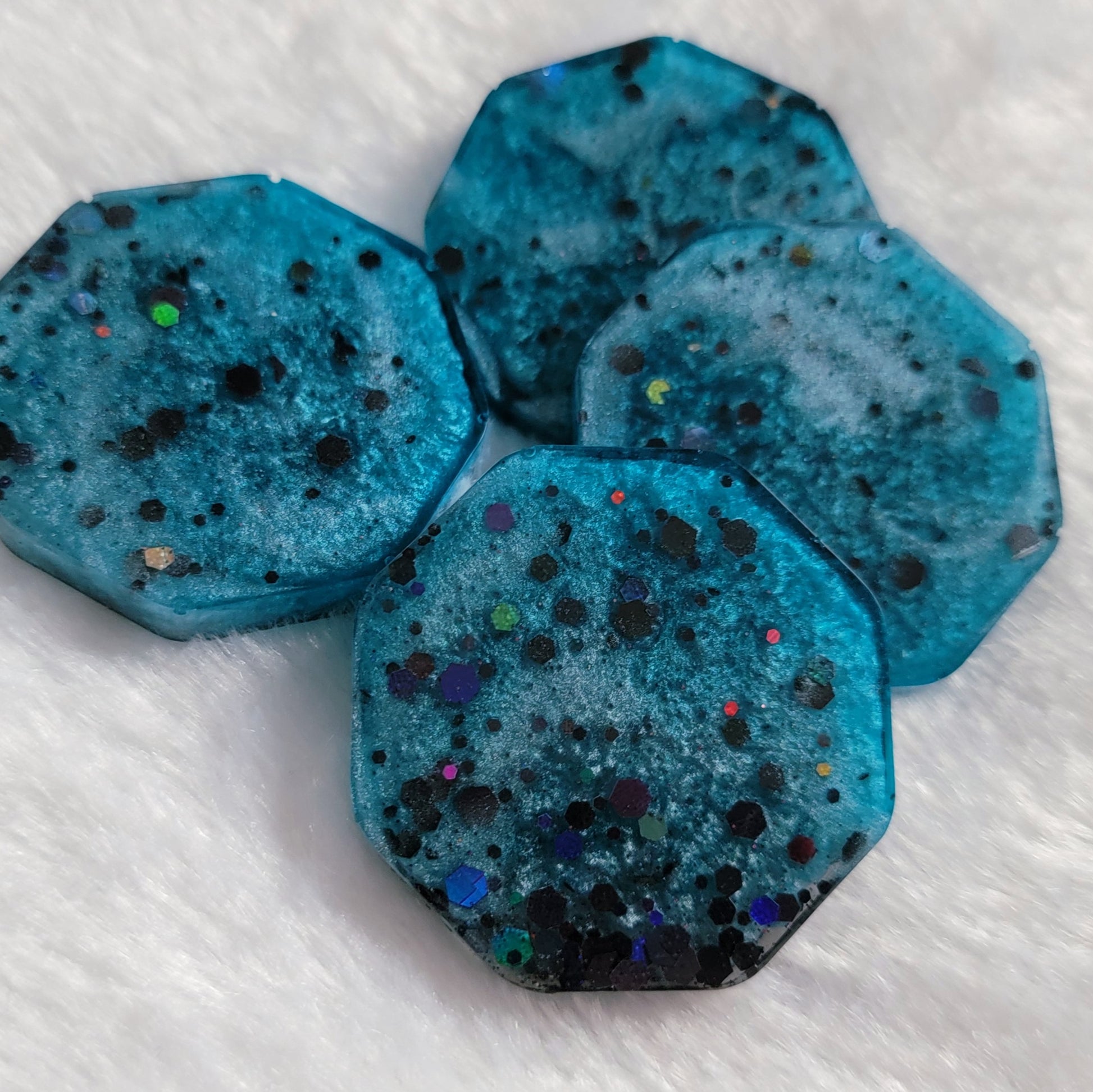 Octagon shaped epoxy resin pieces, light blue swirls with black holographic glitter.