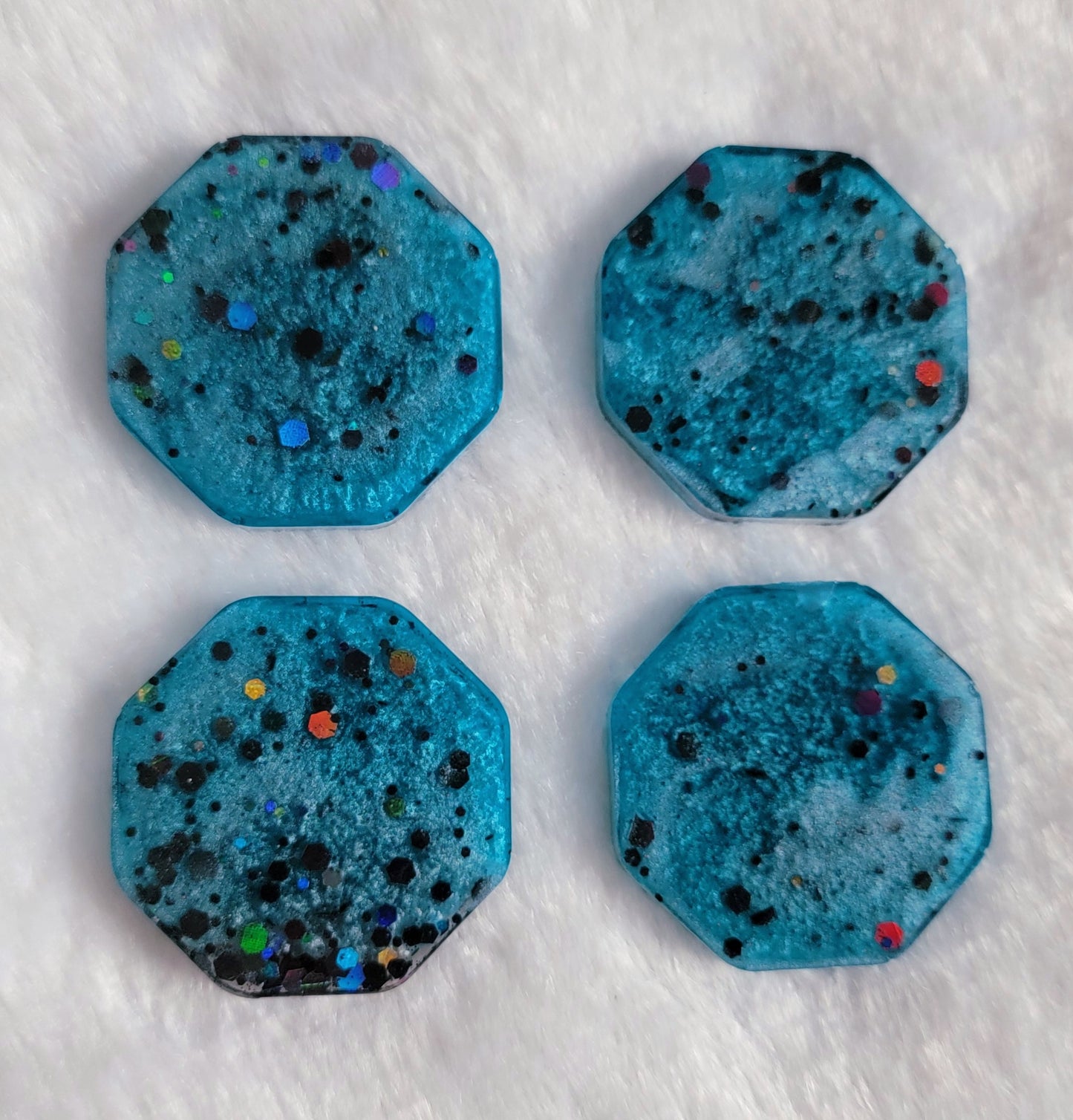 Octagon shaped epoxy resin pieces, light blue swirls with black holographic glitter.