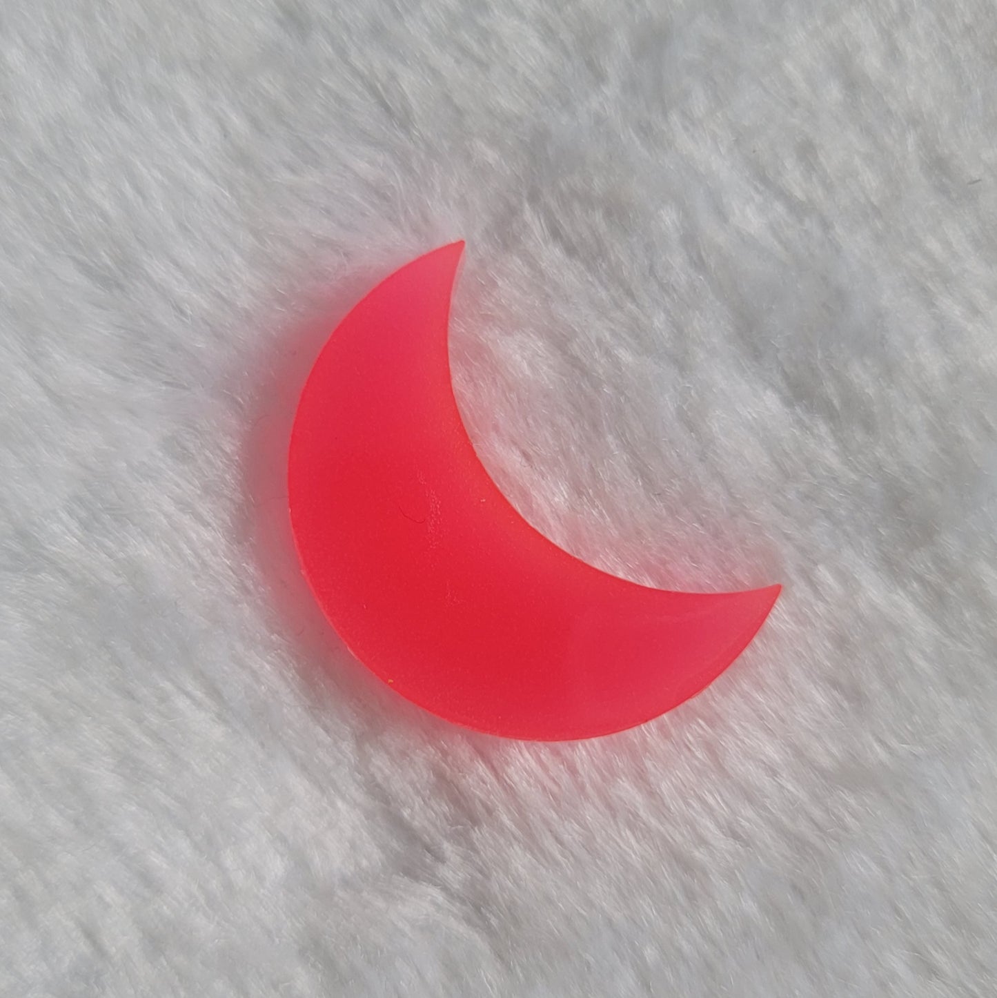 Crescent moon shaped epoxy resin piece, bright coral pink glow in the dark/UV reactive pigment.