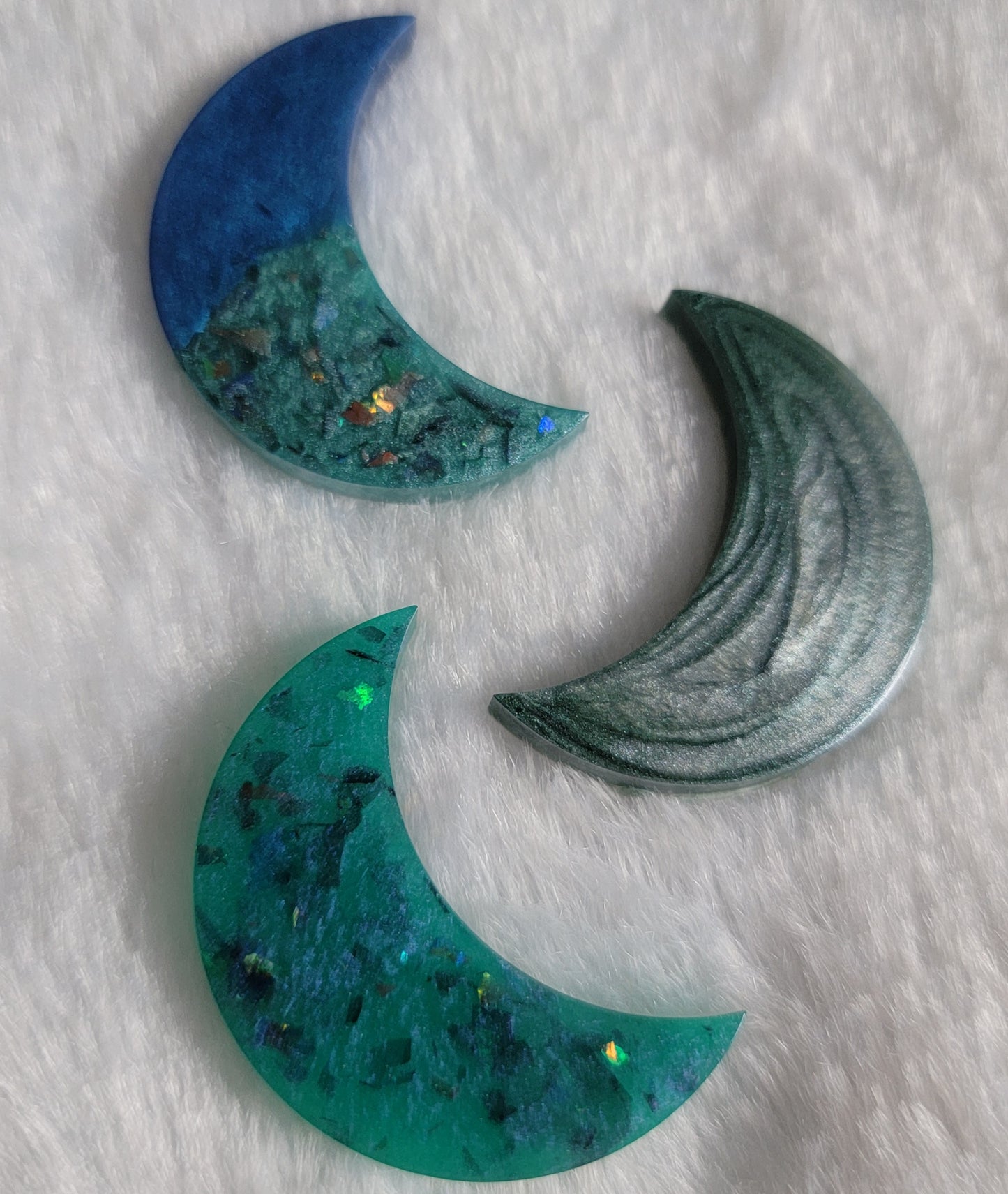 Three crescent moon shaped epoxy resin pieces, shades of blue.