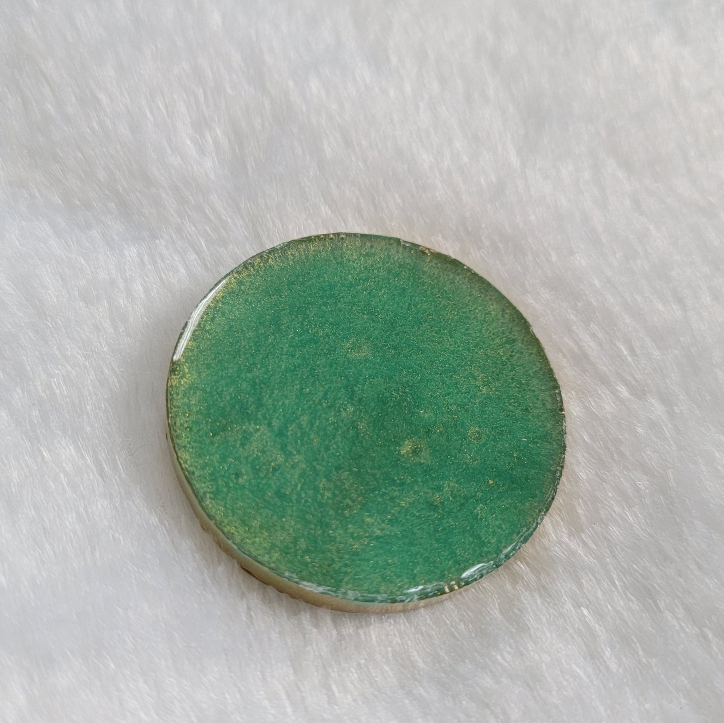 Round epoxy resin piece, bright aqua green back side.