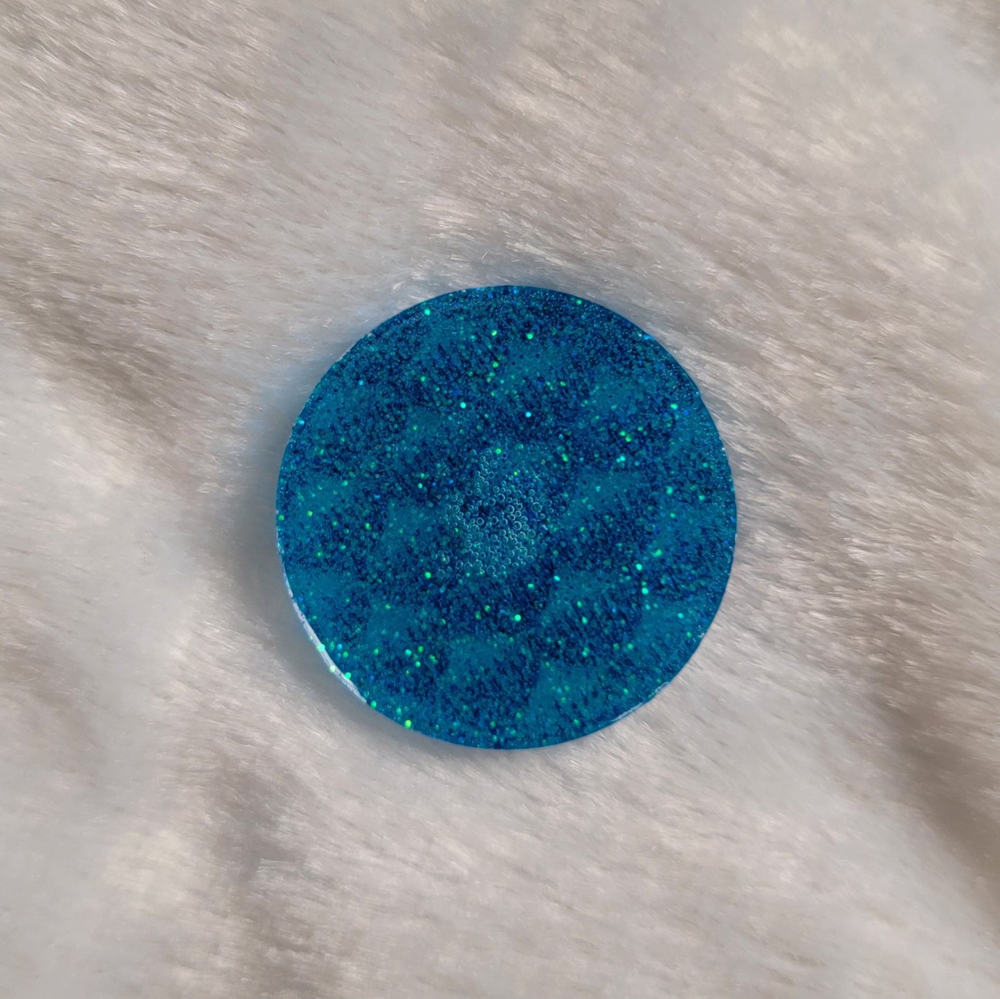 Round epoxy resin piece, light aqua blue glitter back side.