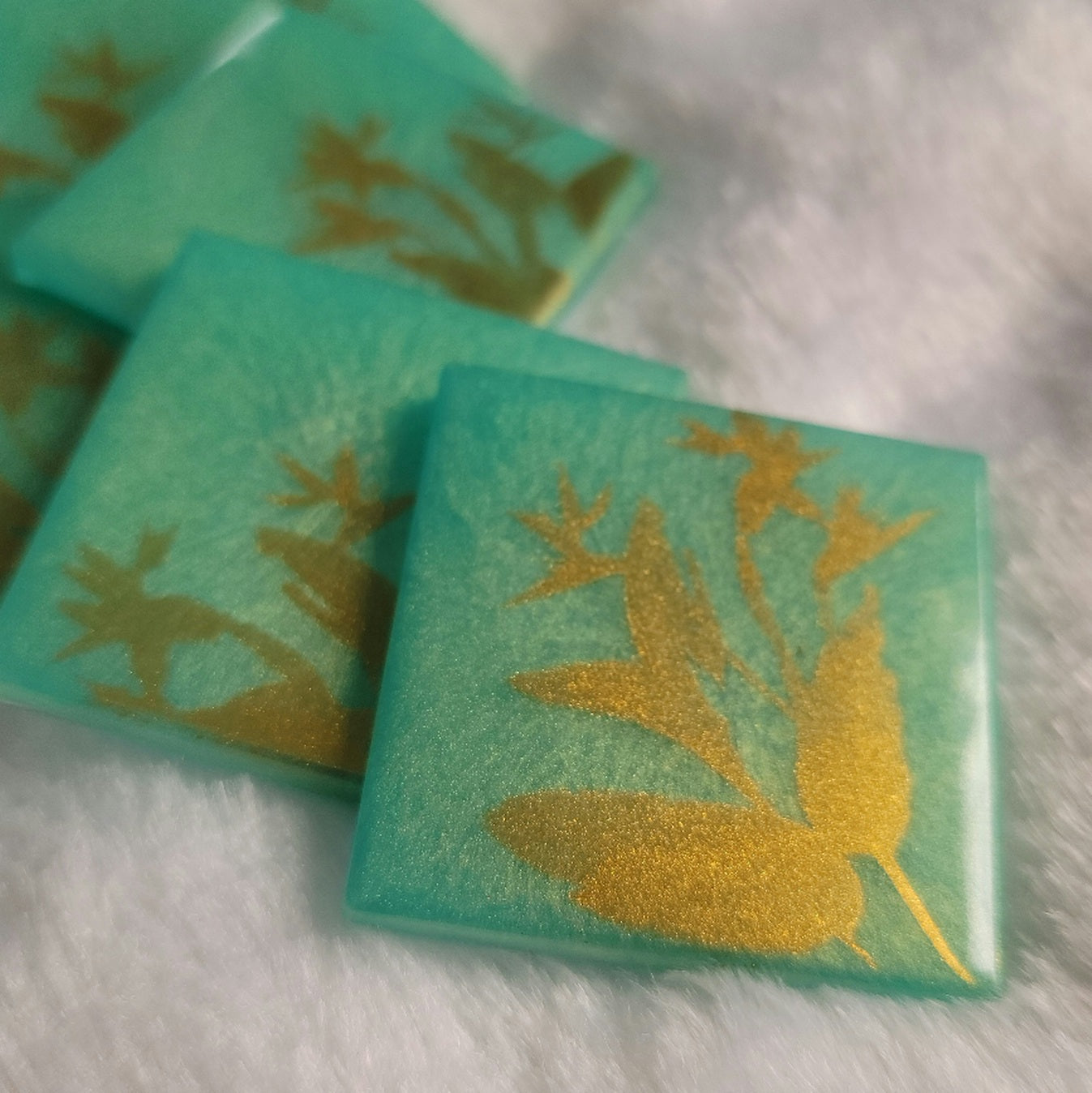 Square epoxy resin pieces, bright aqua green with gold chrome bird of paradise plant design.