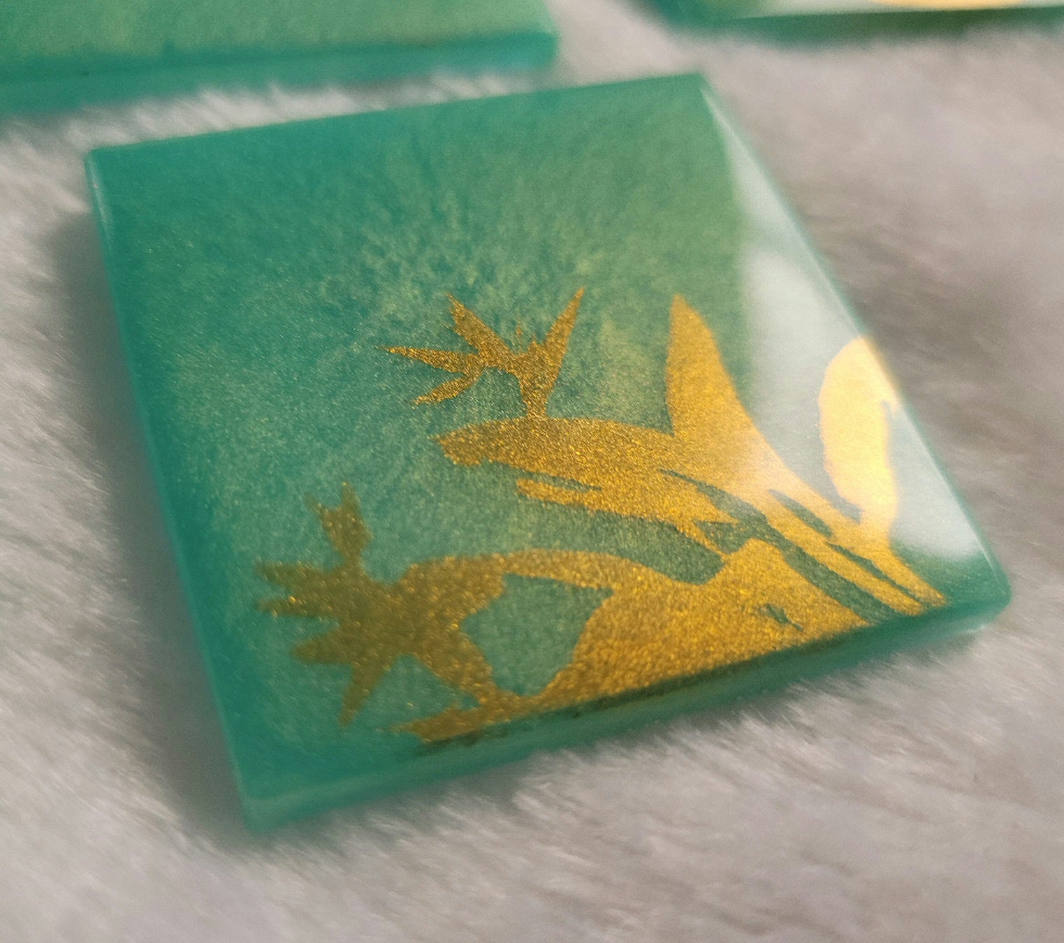 Square epoxy resin piece, bright aqua green with gold chrome bird of paradise plant design.