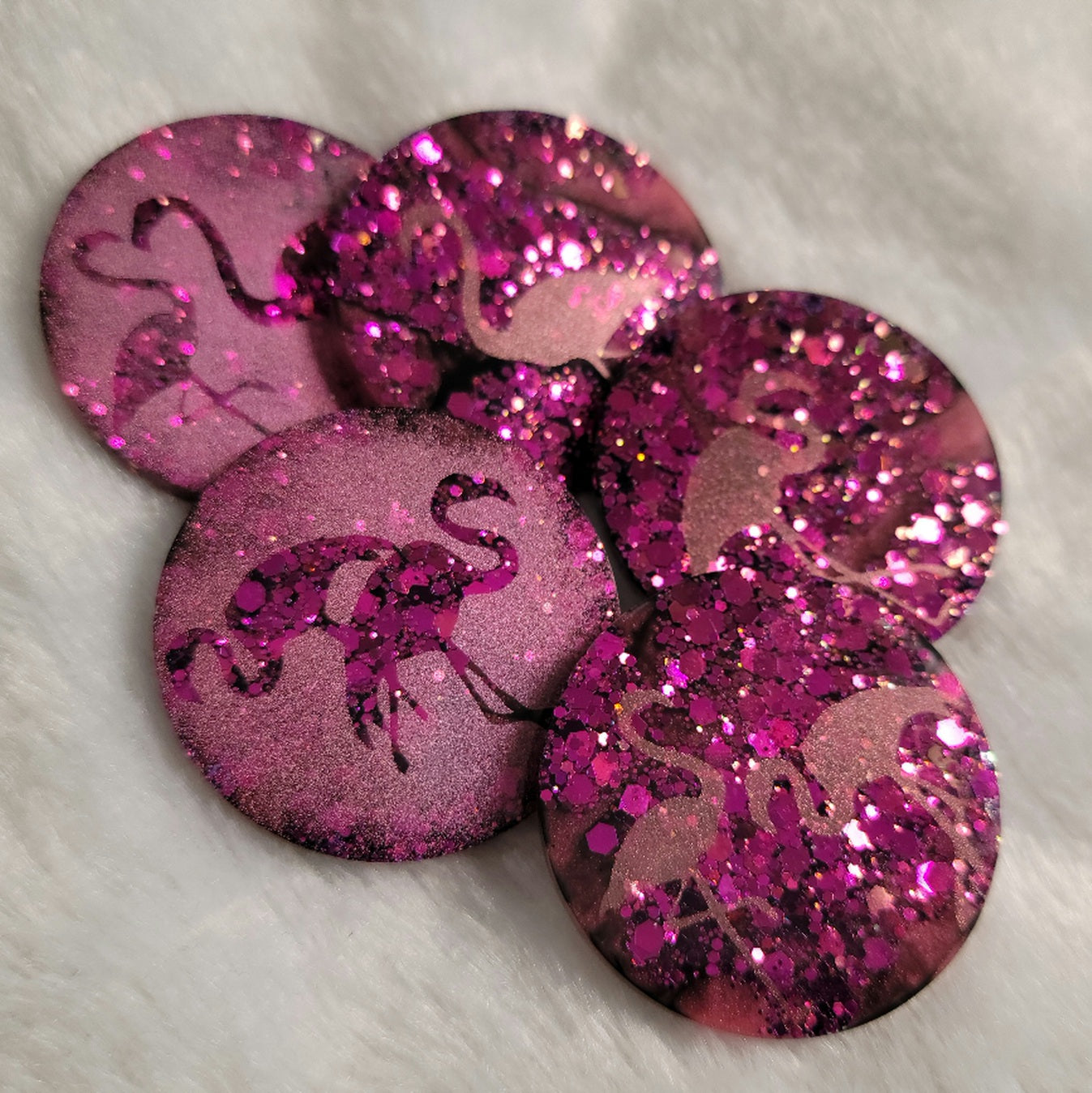 Round epoxy resin pieces, hot pink glitter with metallic flamingo designs. 