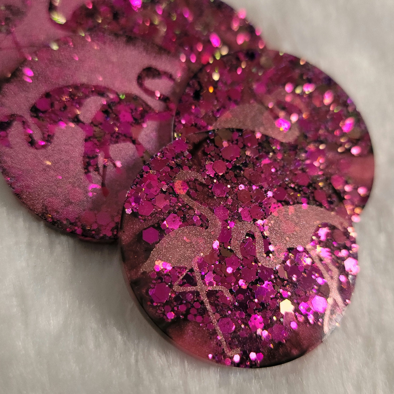 Round epoxy resin pieces, hot pink glitter with metallic flamingo designs. 