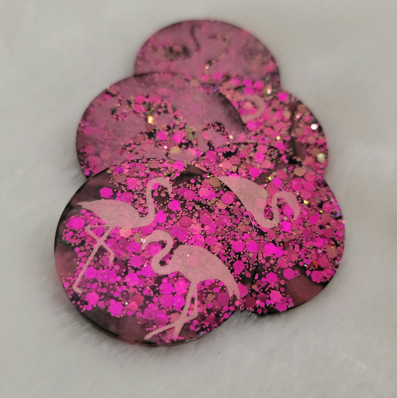 Round epoxy resin pieces, hot pink glitter with metallic flamingo designs. 