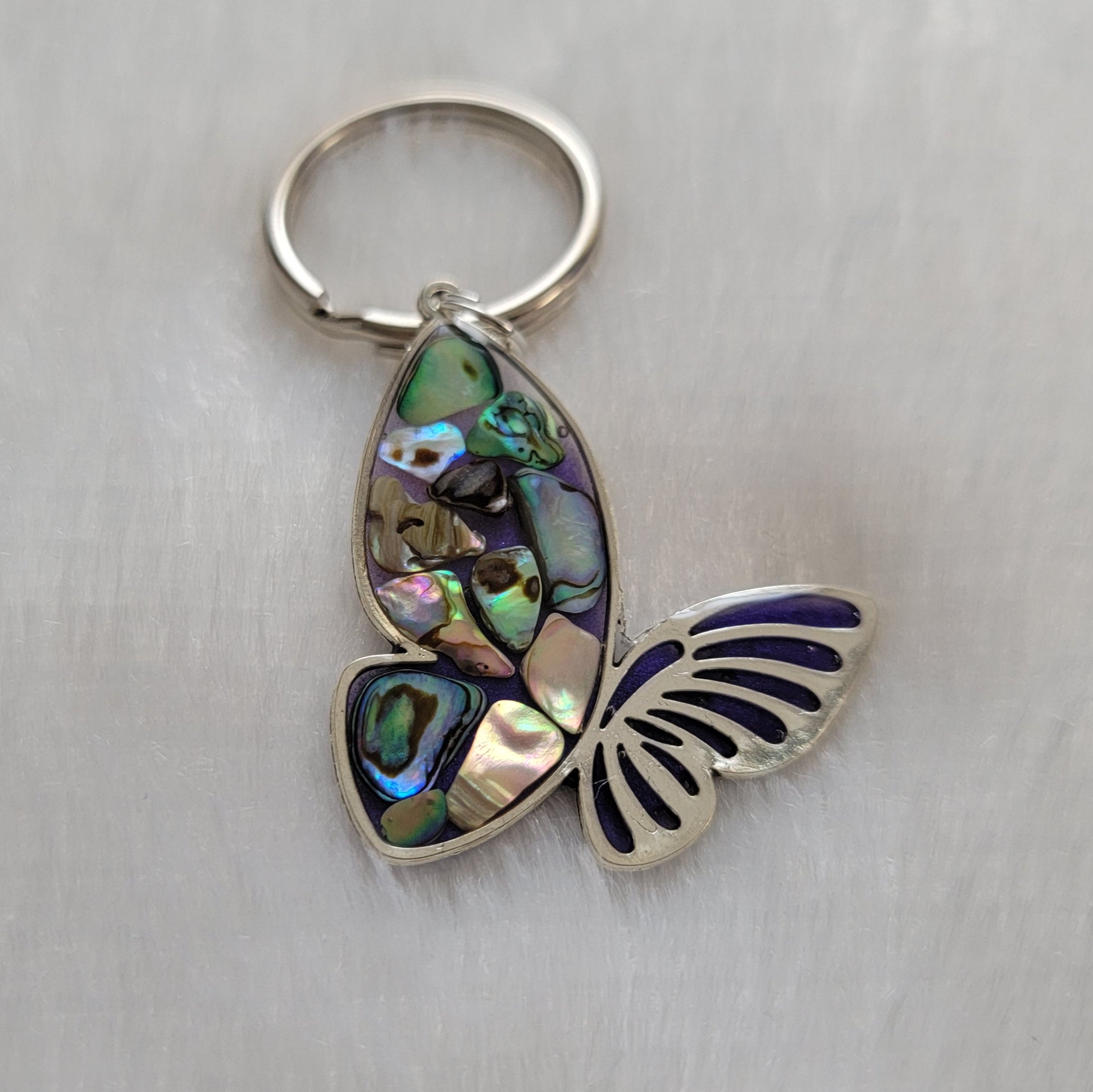 Silver tone metal butterfly charm with rainbow shells and epoxy resin filler.