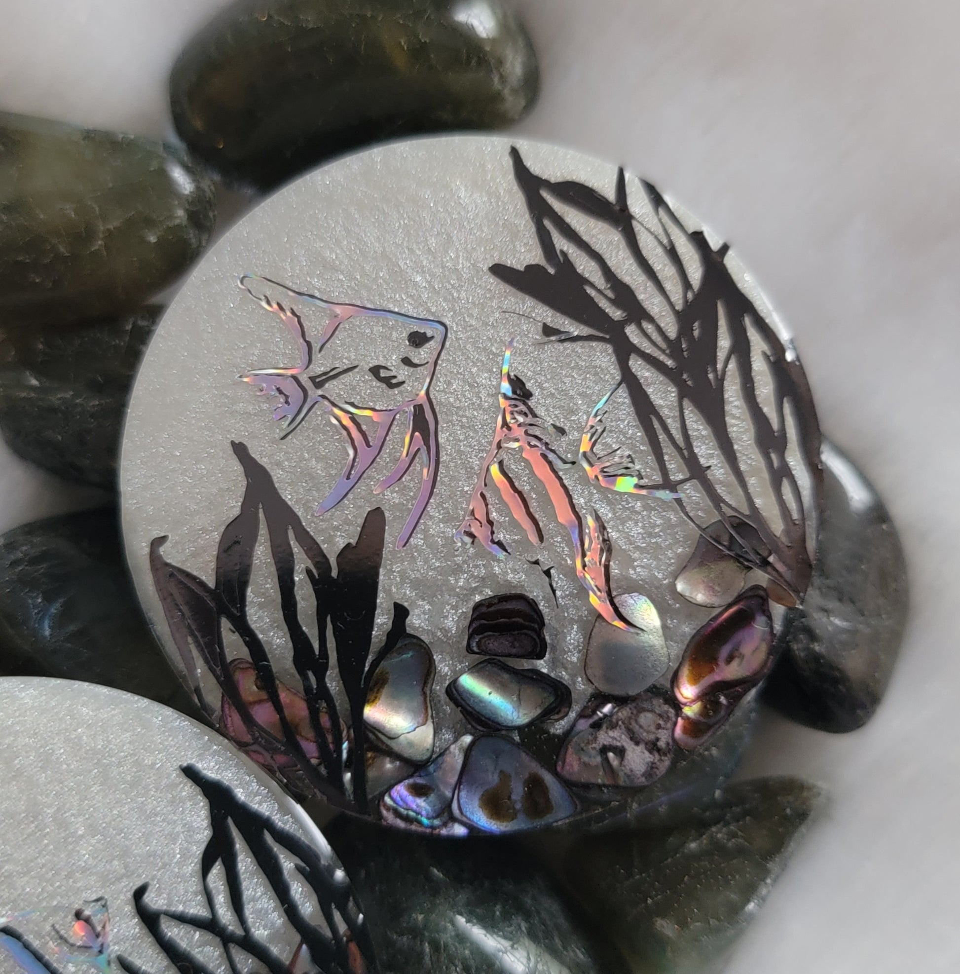 Round epoxy resin piece, pearl white with rainbow shell pieces and holographic vinyl angelfish design.