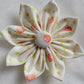 Fabric flower with eight petals and fabric covered button center, print is ivory with yellow-green buds and peach berries.