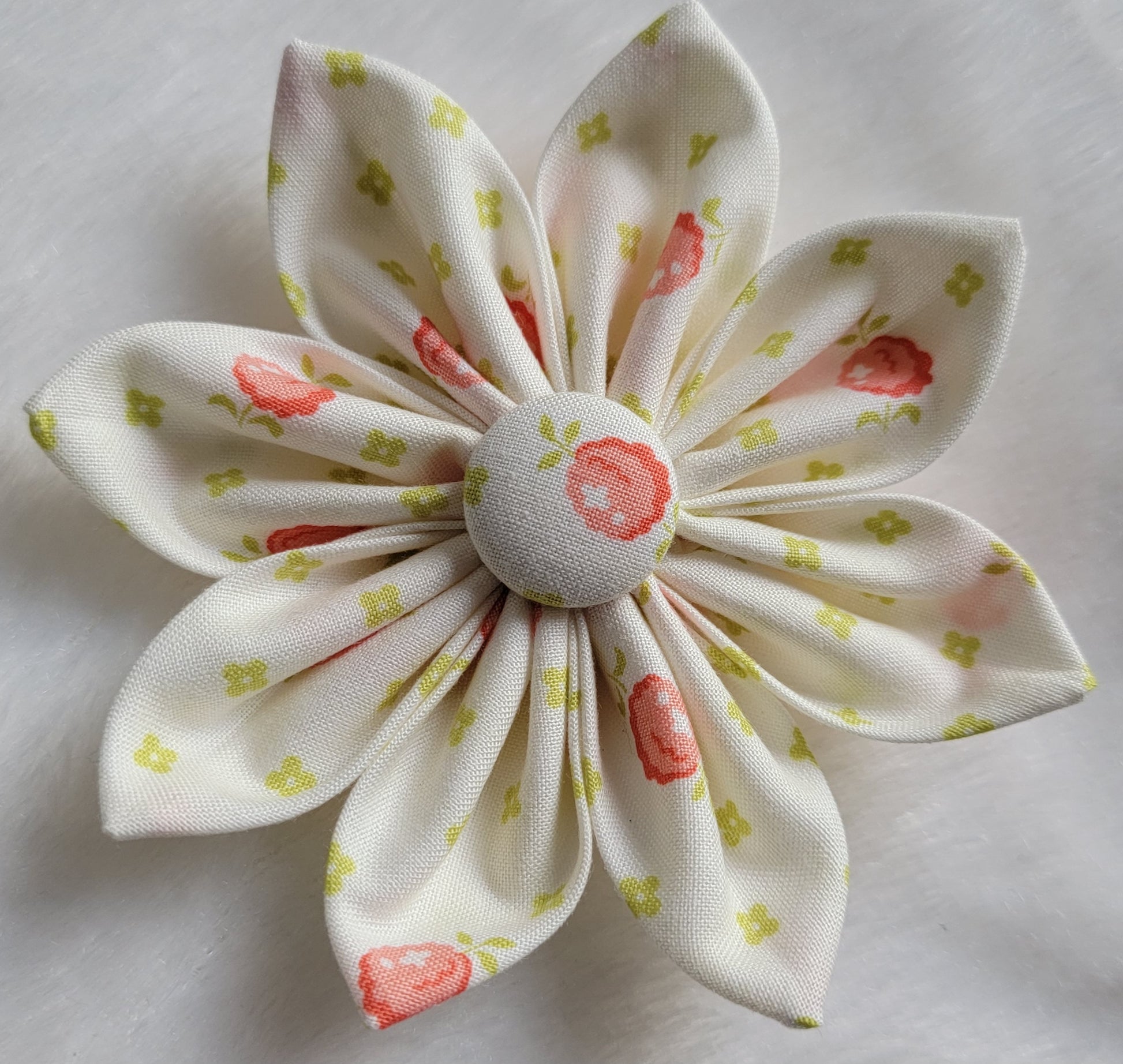 Fabric flower with eight petals and fabric covered button center, print is ivory with yellow-green buds and peach berries.