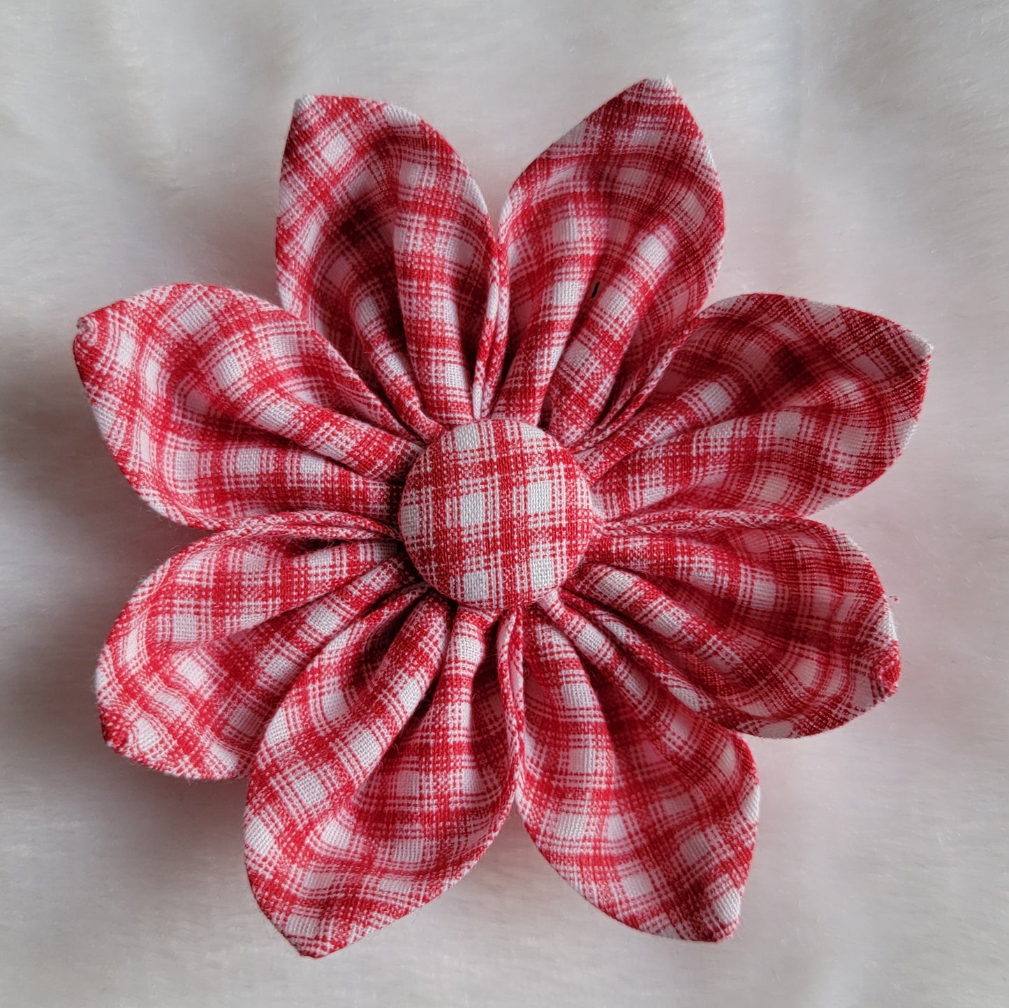 Fabric flower with eight petals and fabric covered button center, print is red and white plaid.