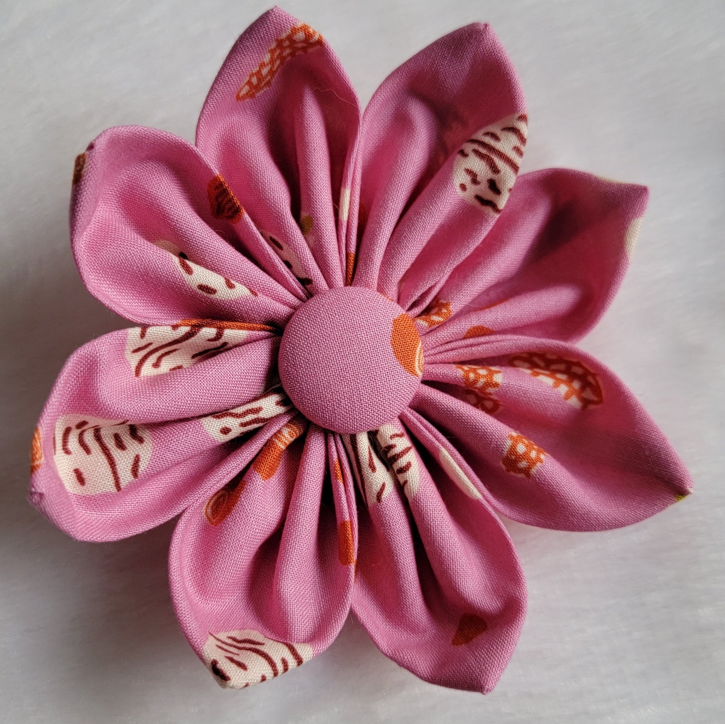 Fabric flower with eight petals and fabric covered button center, print is a rich mauve with mixed nuts.