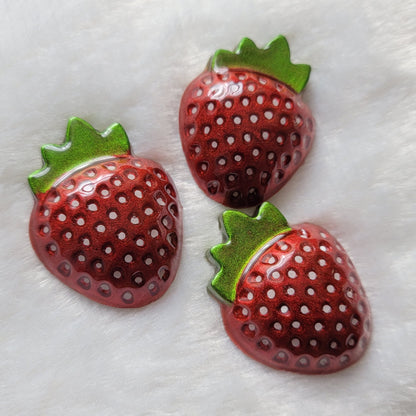 Three strawberry shaped epoxy resin pieces, bright metallic red pigment with hand painted white seeds and leaves in chrome green.