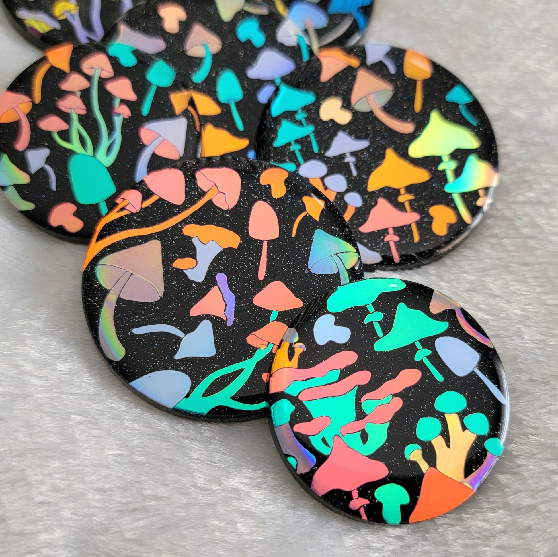 Round sparkly black epoxy resin pieces with multicolored holographic mushrooms design.