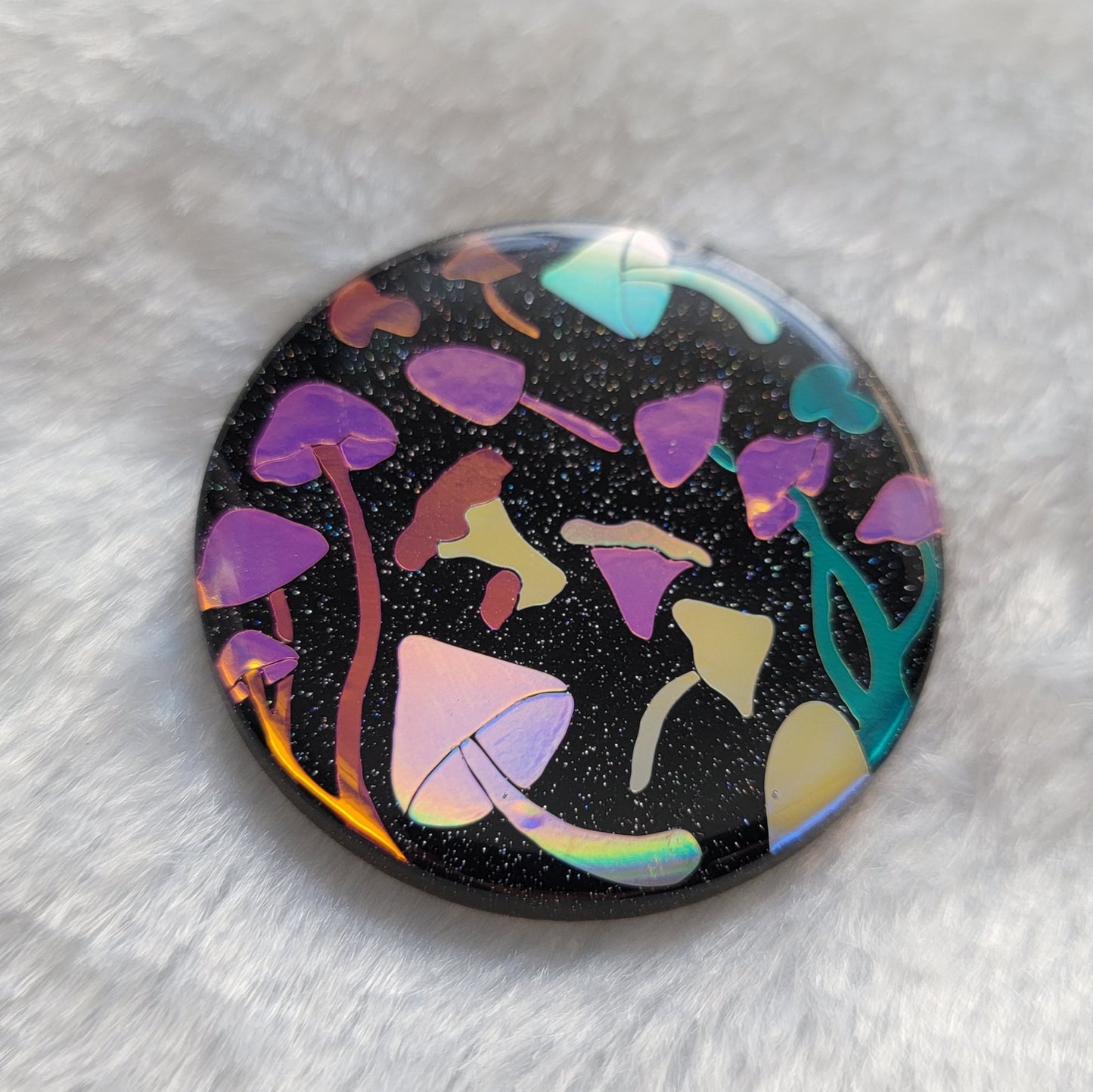 Round sparkly black epoxy resin piece with multicolored holographic mushrooms design.