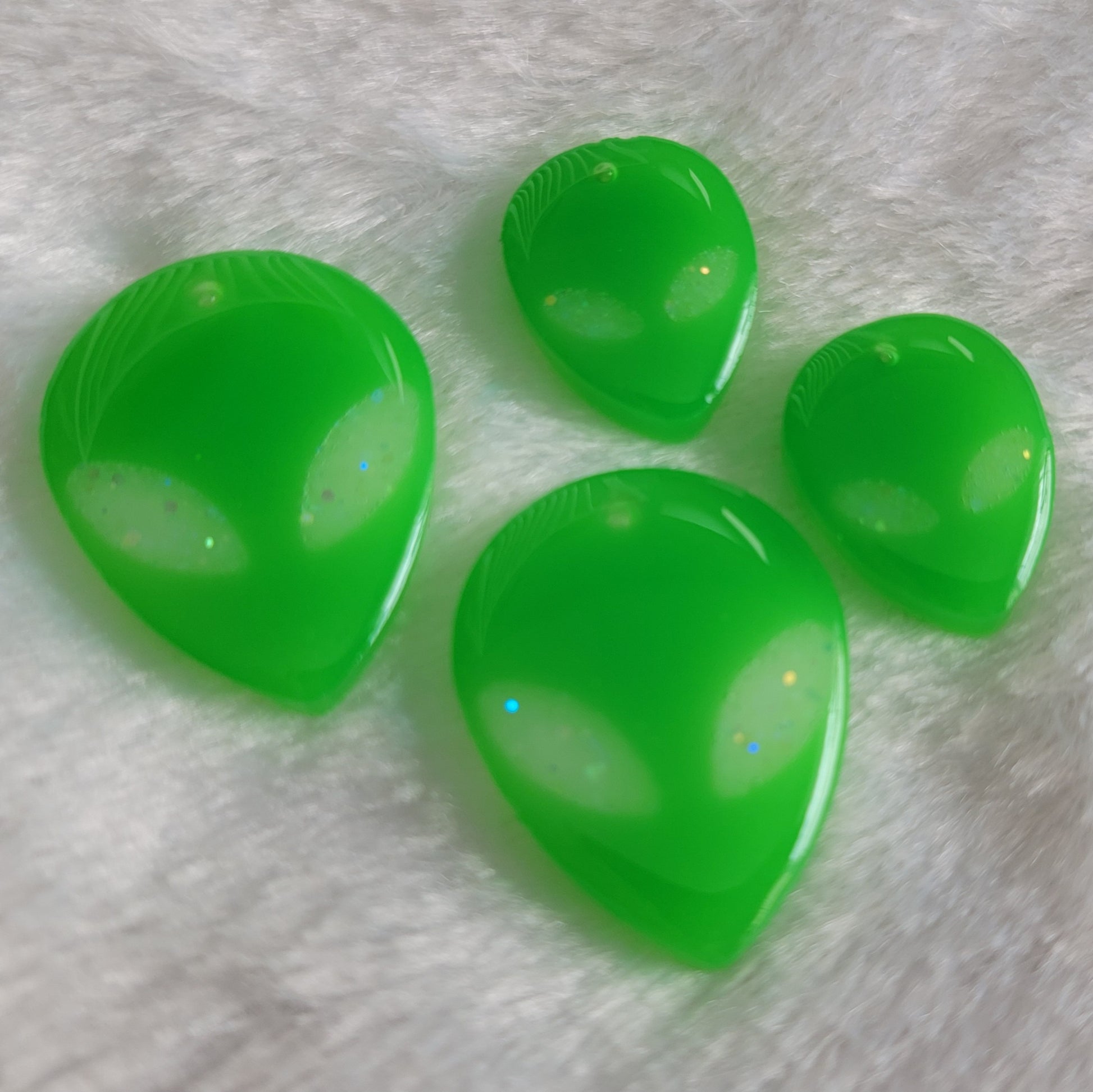 Bright green UV reactive alien head shaped epoxy resin pieces.