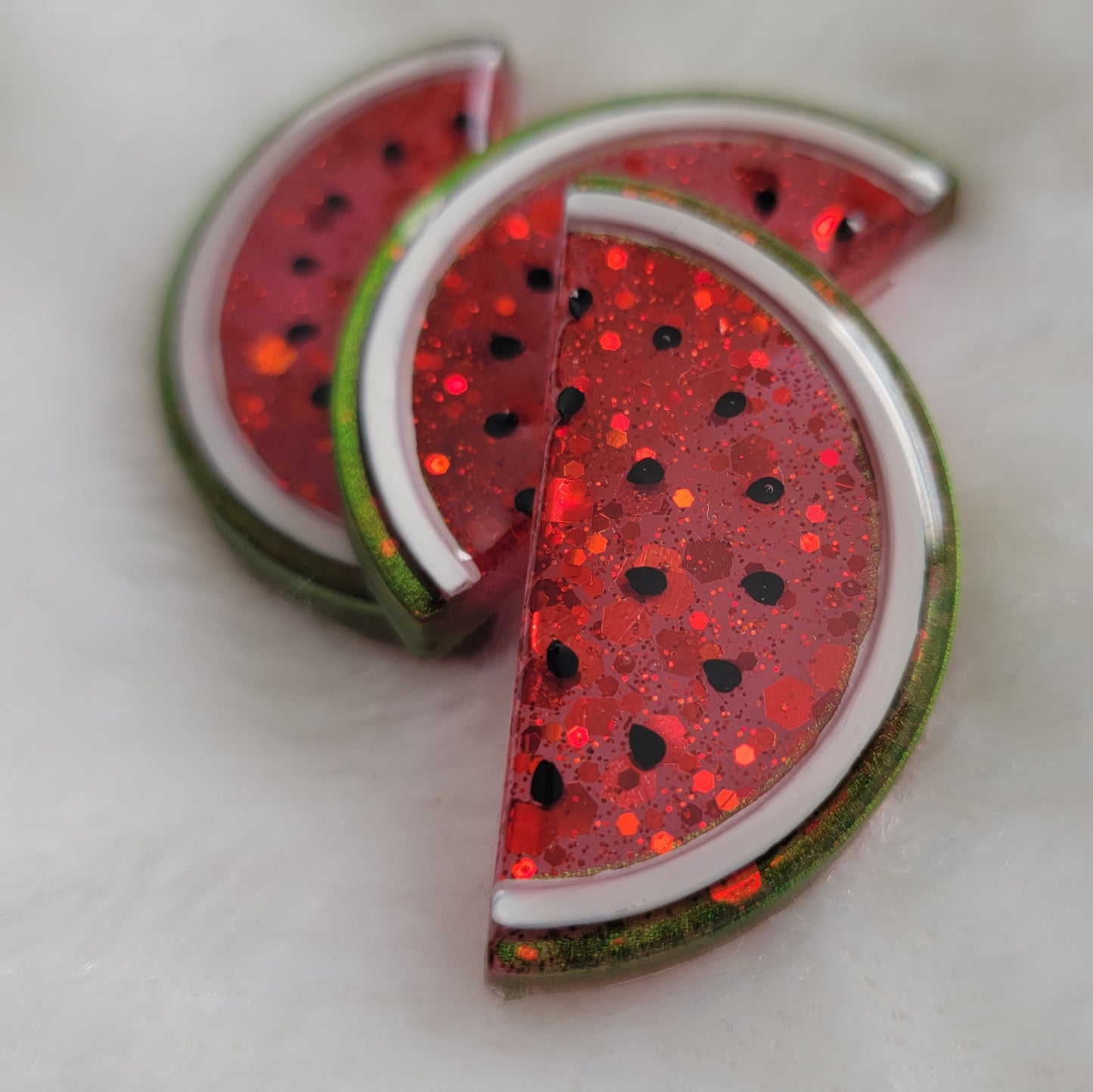 Red semi-translucent glittery watermelon slice shaped epoxy resin pieces.