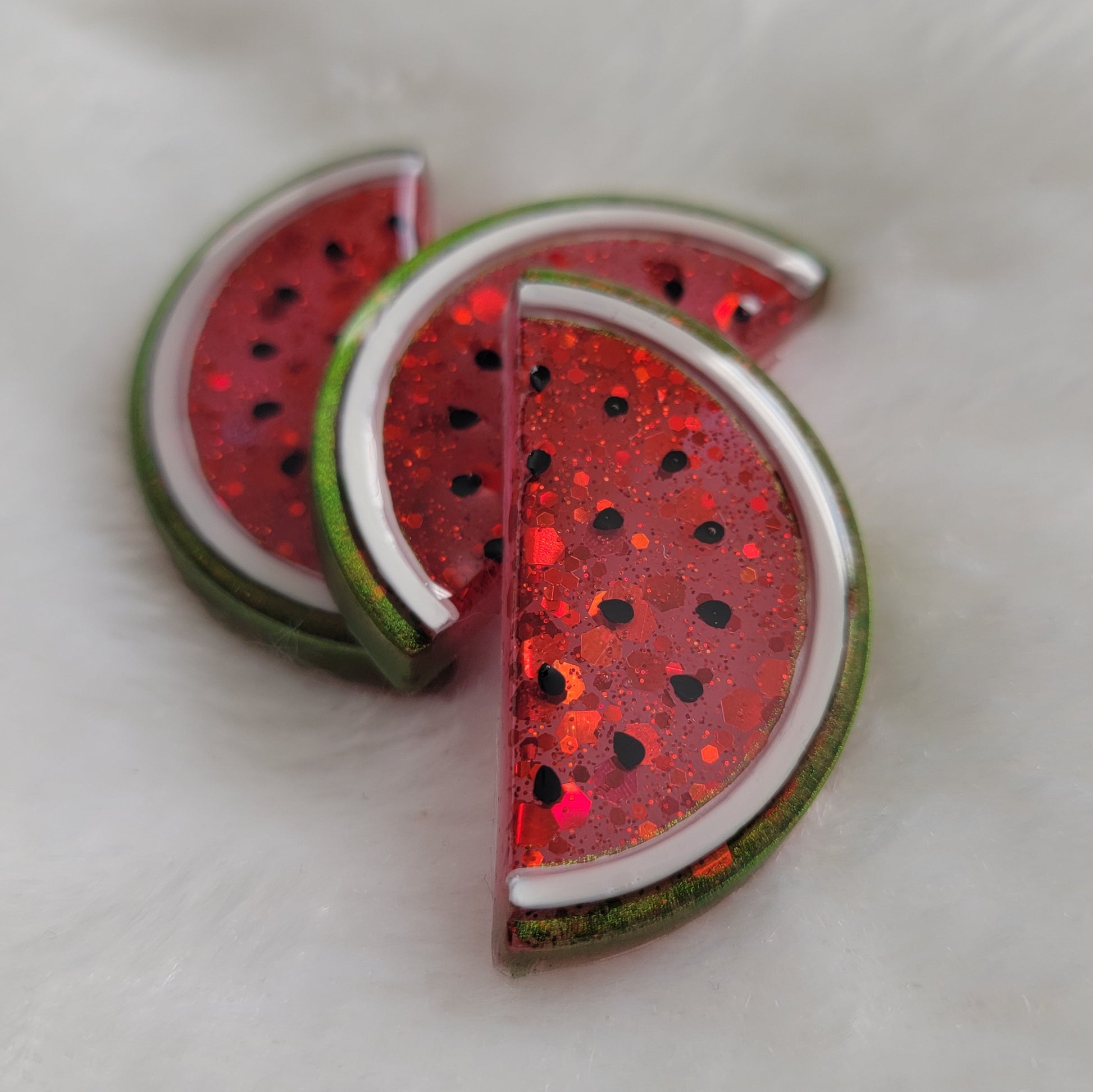 Red semi-translucent glittery watermelon slice shaped epoxy resin pieces.