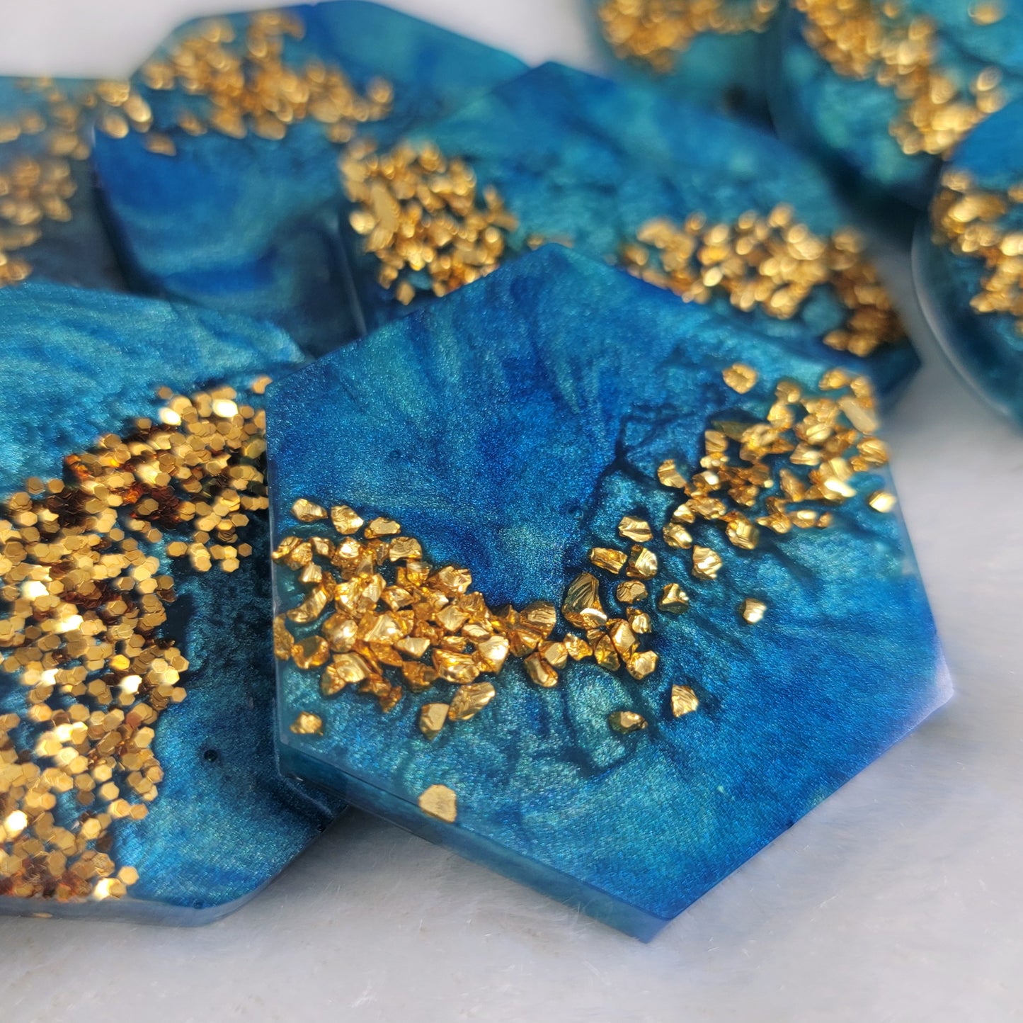 Epoxy resin pieces blue mica swirls and gold glitter and gold glass glitter.