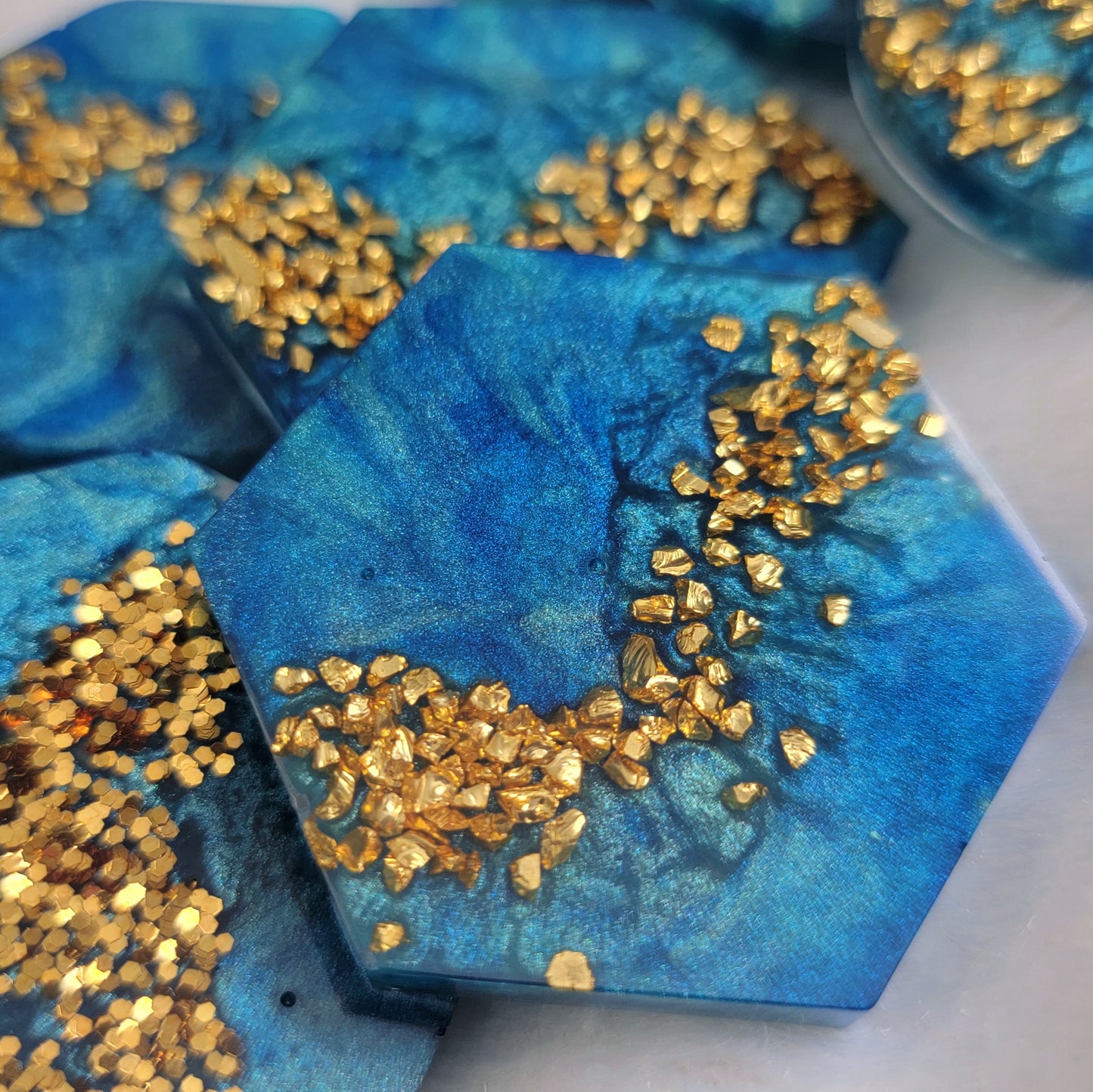 Epoxy resin pieces blue mica swirls and gold glitter and gold glass glitter.