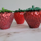 Epoxy resin trinket dishes shaped like strawberries.