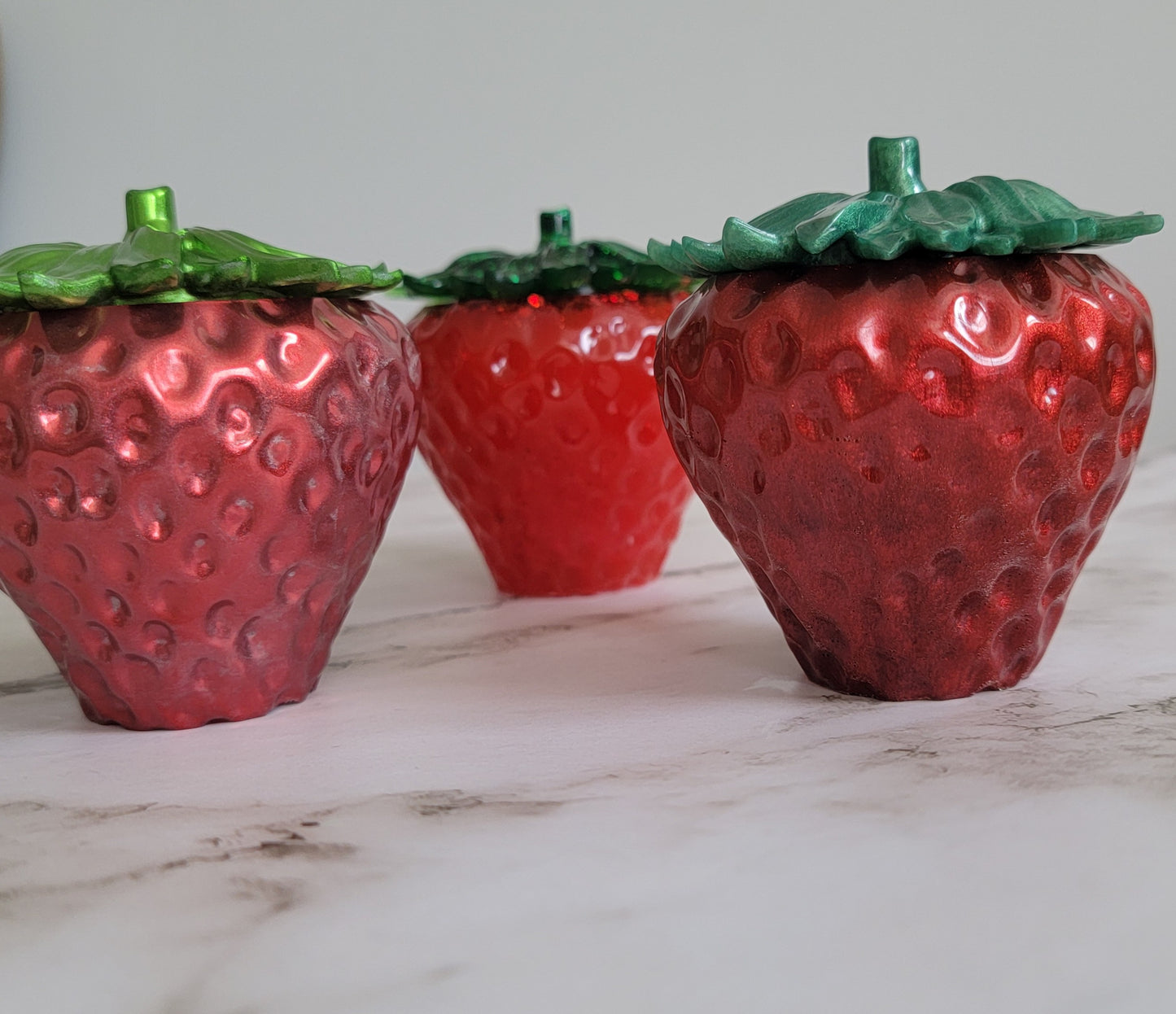 Epoxy resin trinket dishes shaped like strawberries.