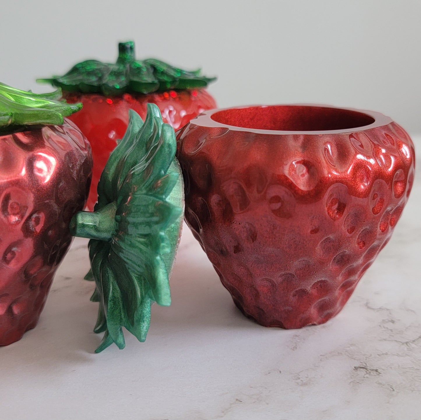 Epoxy resin trinket dishes shaped like strawberries.