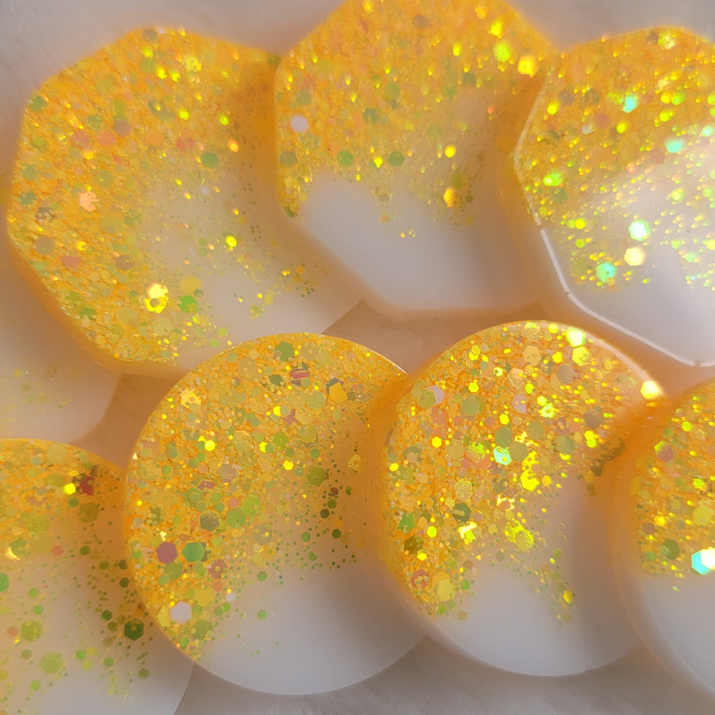 Epoxy resin pieces with ultra bright yellow holographic glitter fading to opaque white pigment.