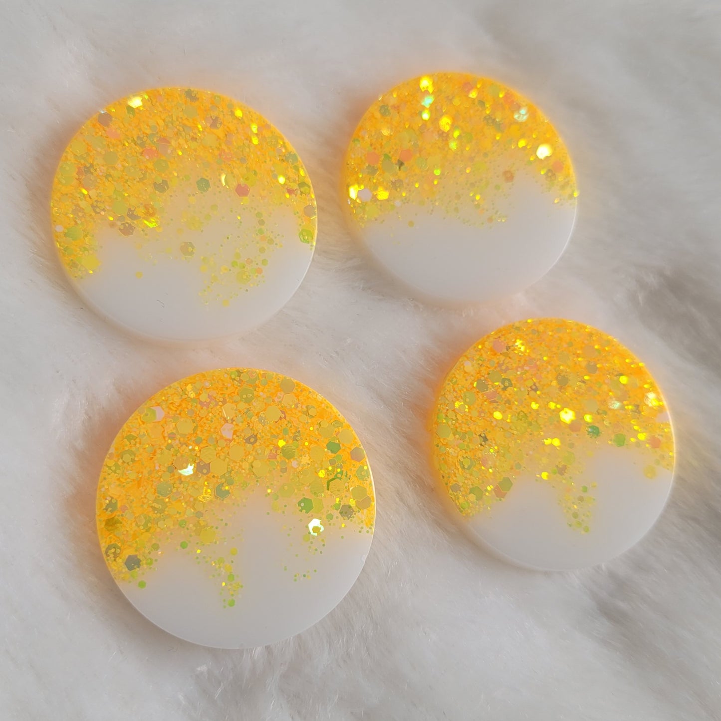 Four round epoxy resin pieces with ultra bright yellow holographic glitter fading to opaque white pigment.