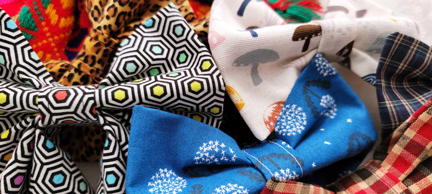 Fabric bowties and sailor bows shown in various prints including: rainbow geometric, leopard print, blue with dandelions, mushrooms on off-white, and plaid.