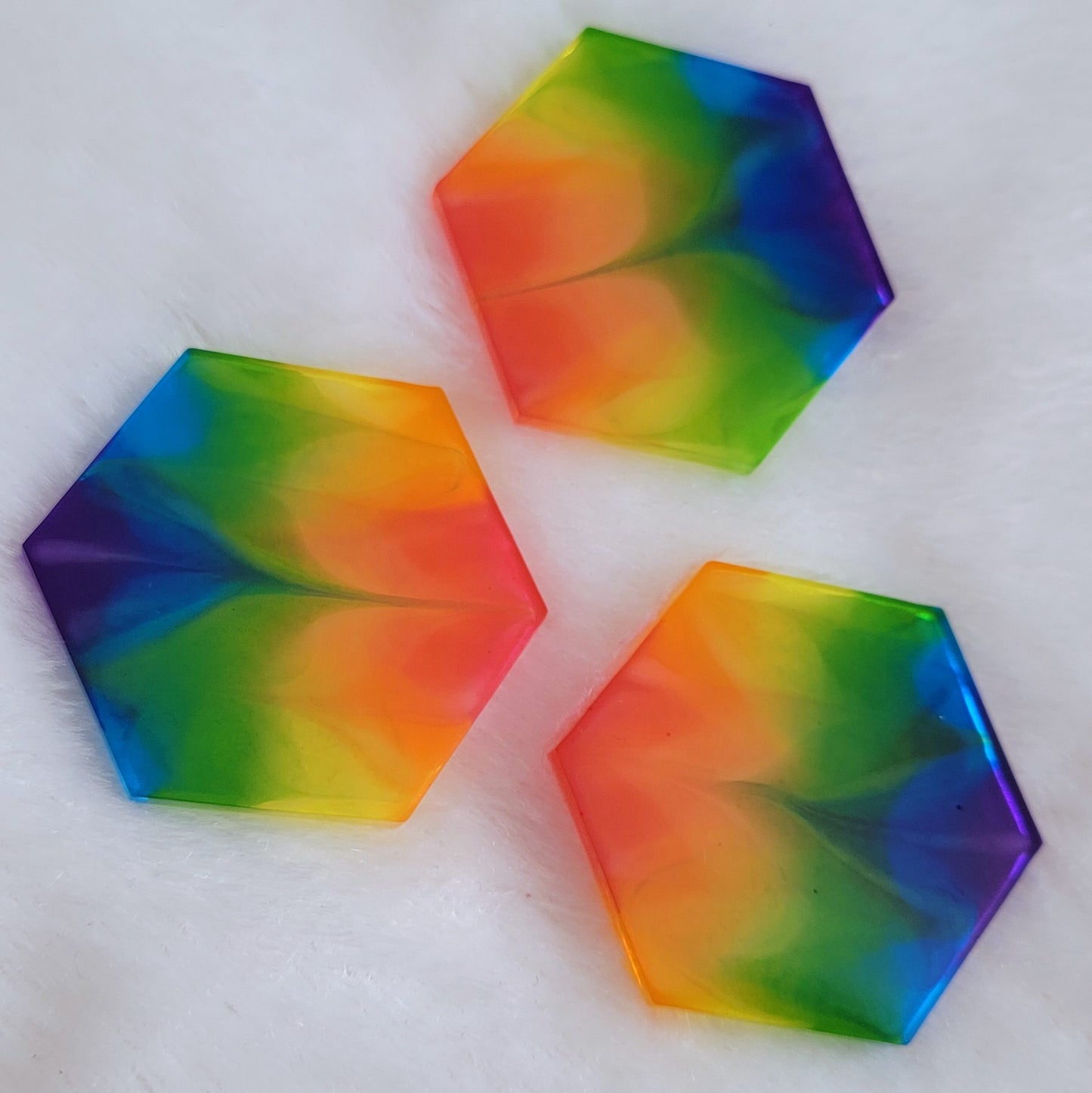 Three hexagon shaped epoxy resin pieces with zigzag design through translucent rainbow color stripes.