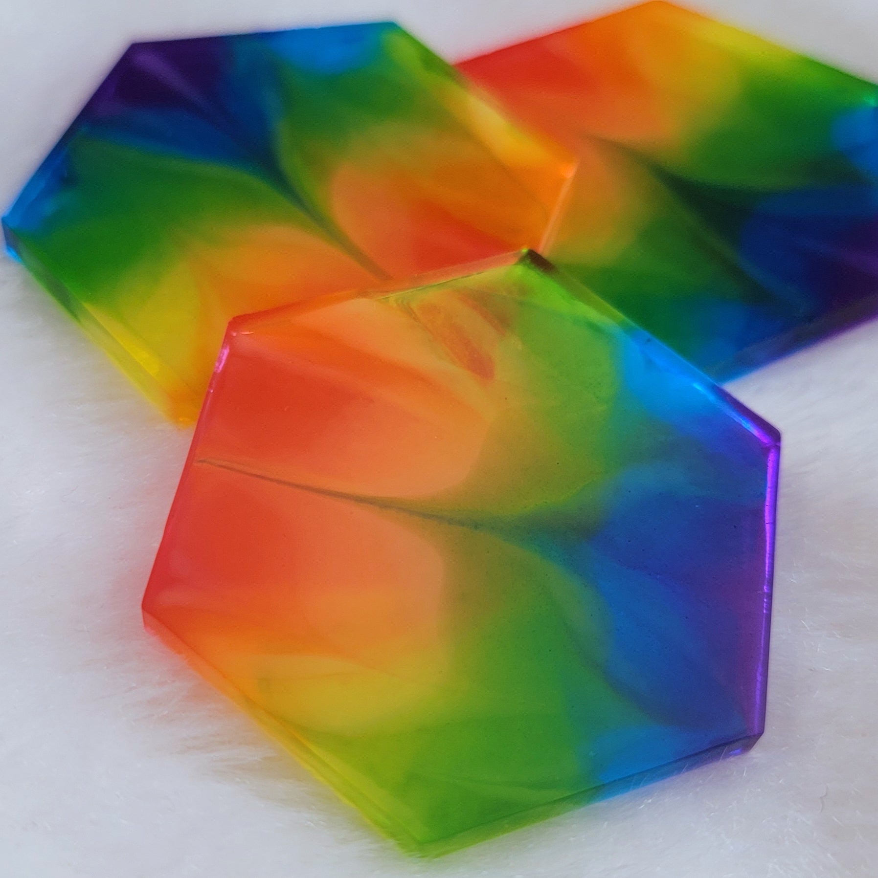 Three hexagon shaped epoxy resin pieces with zigzag design through translucent rainbow color stripes.