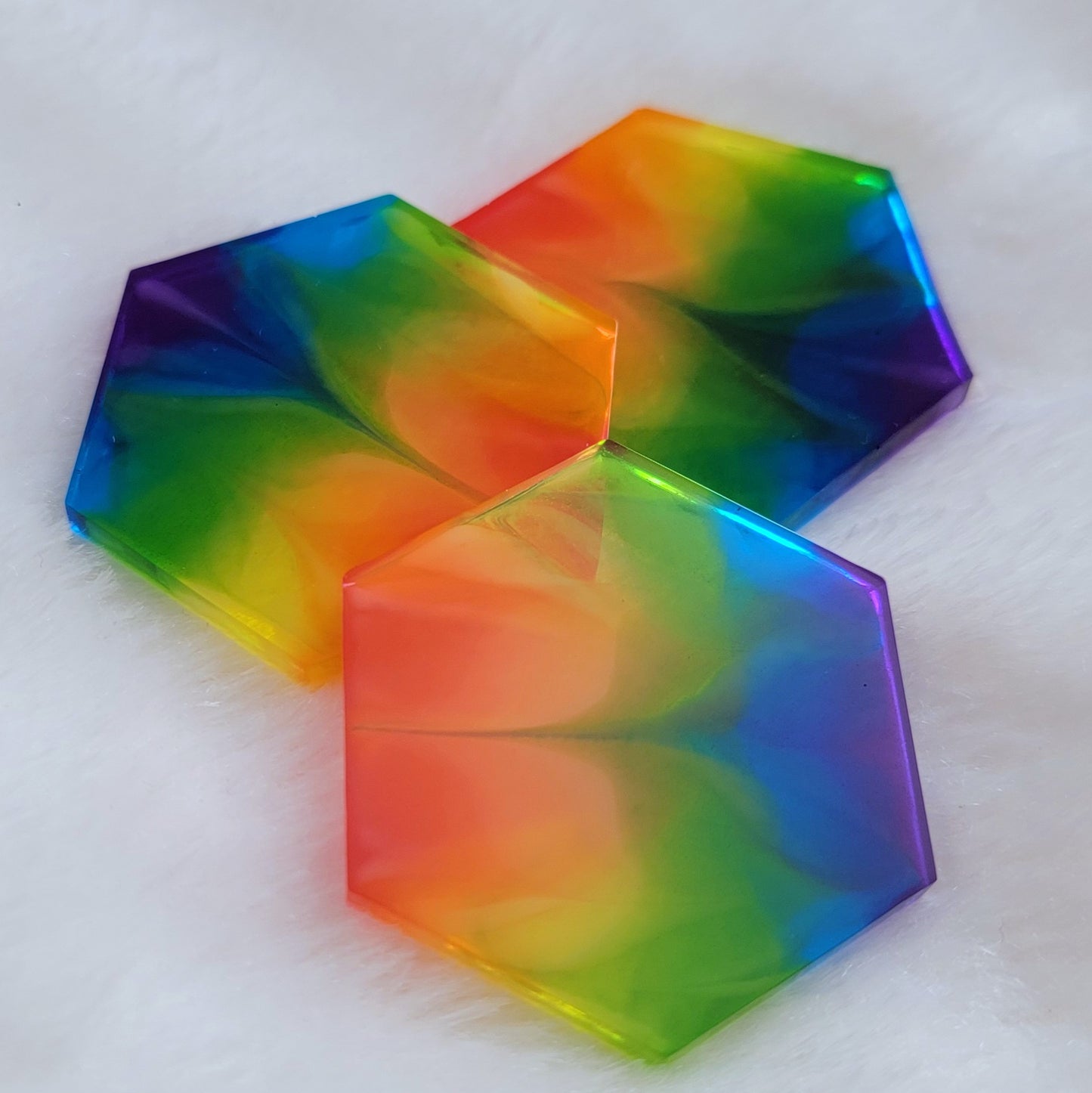 Three hexagon shaped epoxy resin pieces with zigzag design through translucent rainbow color stripes.