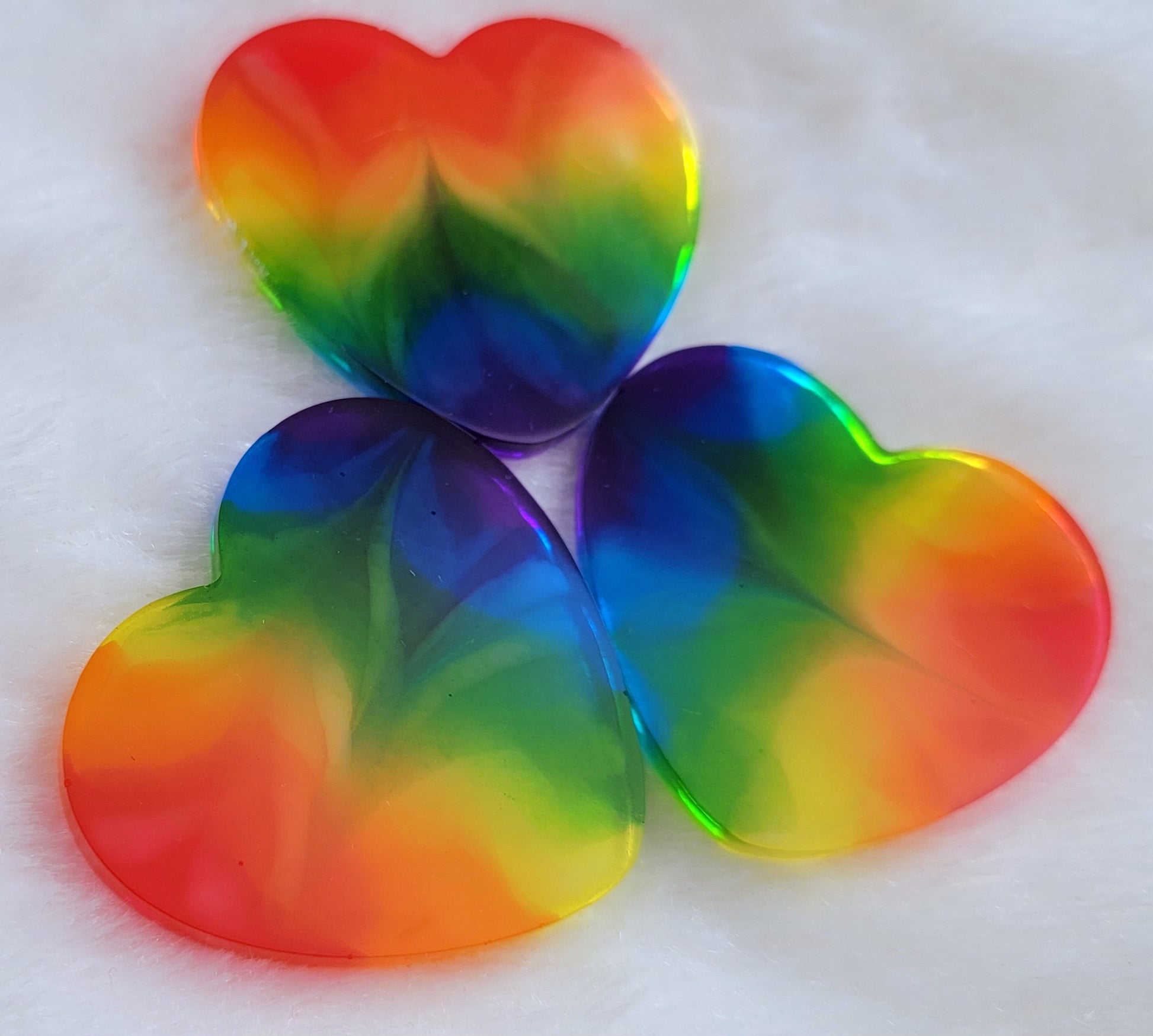 Three heart shaped epoxy resin pieces with zigzag design through translucent rainbow color stripes.