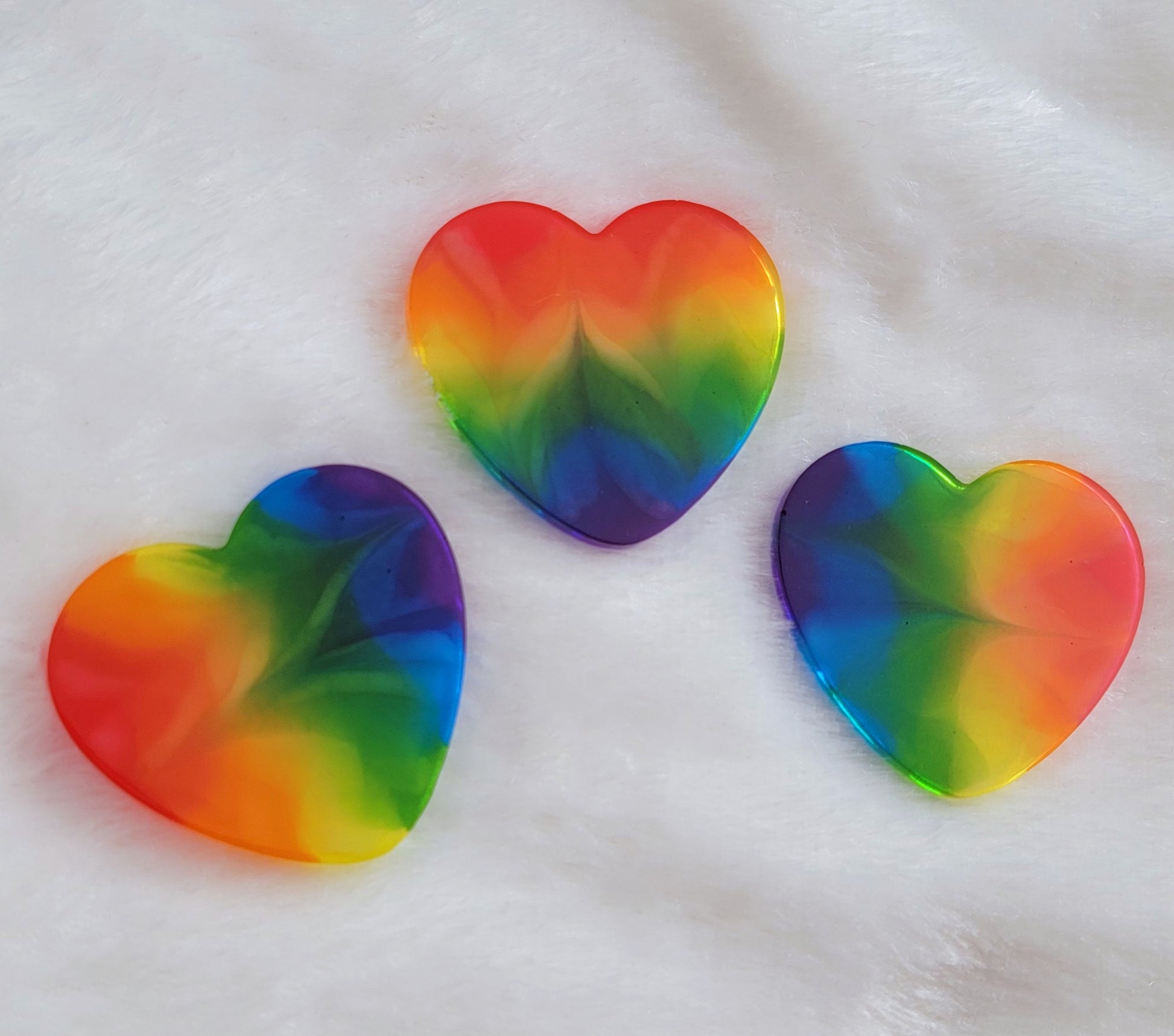 Three heart shaped epoxy resin pieces with zigzag design through translucent rainbow color stripes.