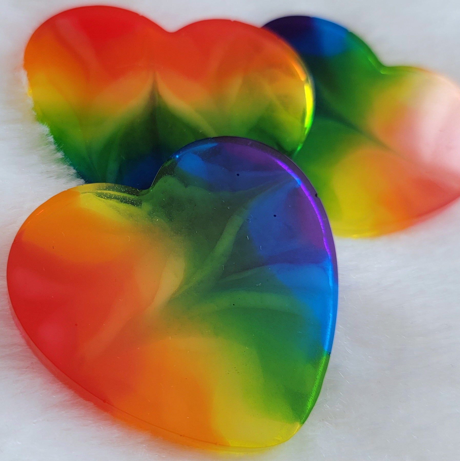 Three heart shaped epoxy resin pieces with zigzag design through translucent rainbow color stripes.