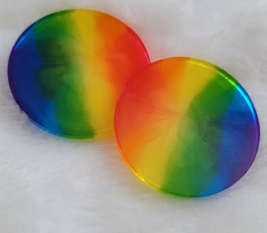 Two round epoxy resin pieces with subtle bloom effect in translucent rainbow stripes.