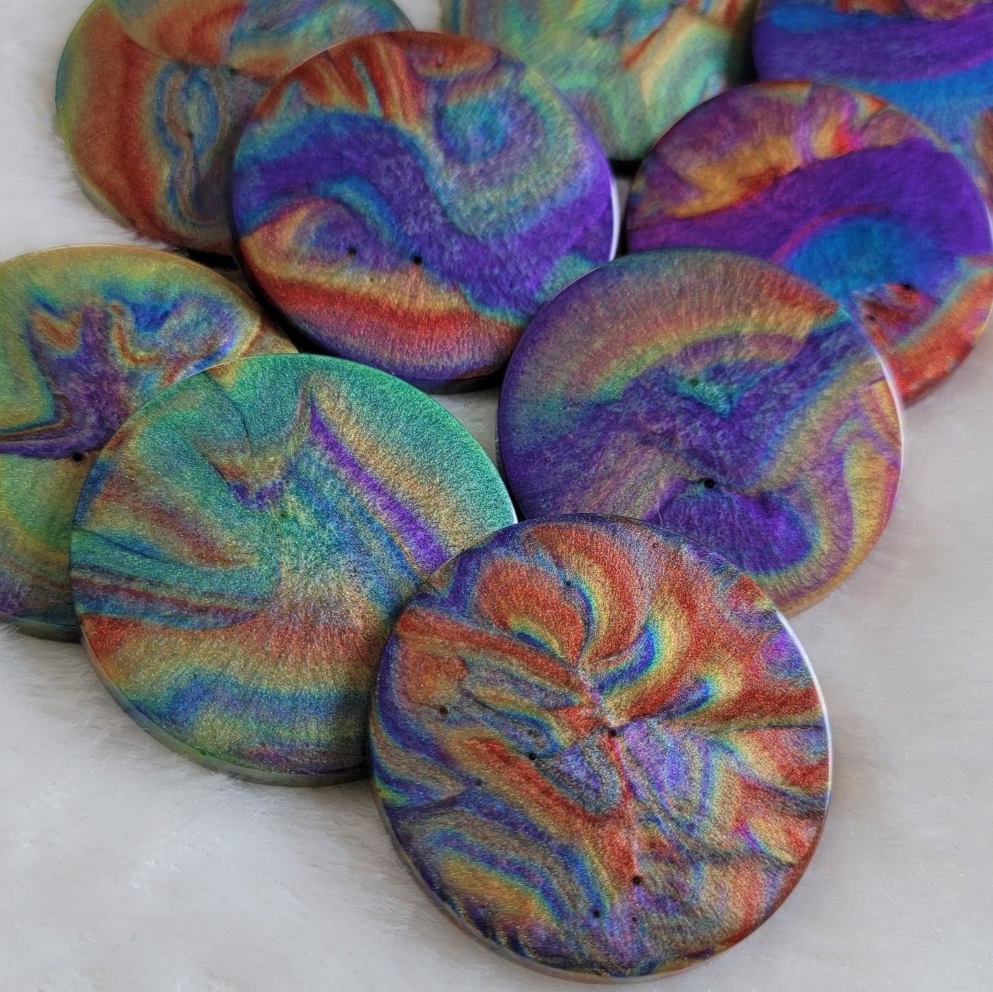 Several round epoxy resin pieces with colorful shimmering psychedelic swirls.