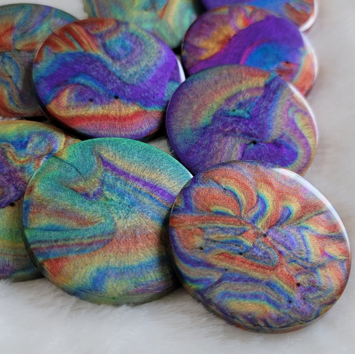 Several round epoxy resin pieces with colorful shimmering psychedelic swirls.