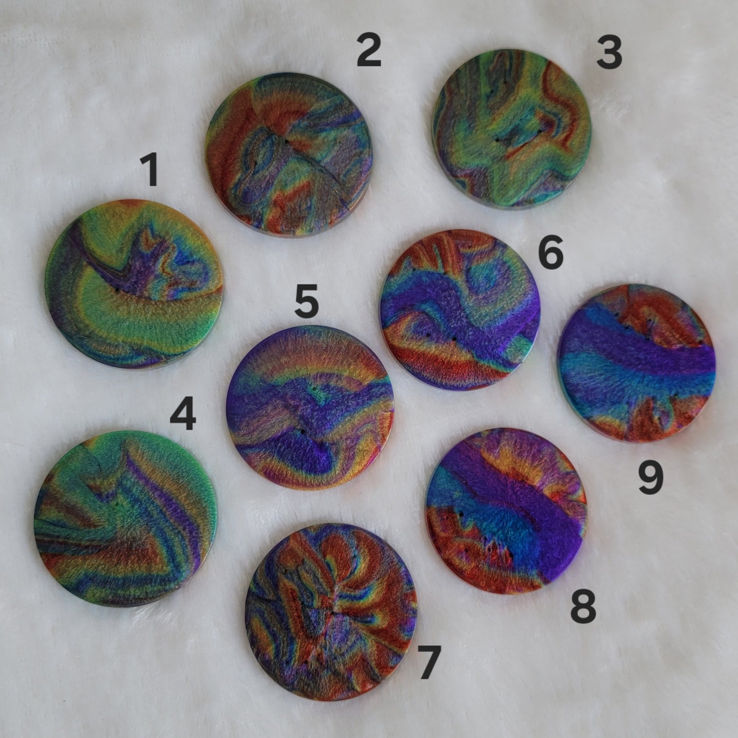 Nine available round epoxy resin pieces with colorful shimmering psychedelic swirls.