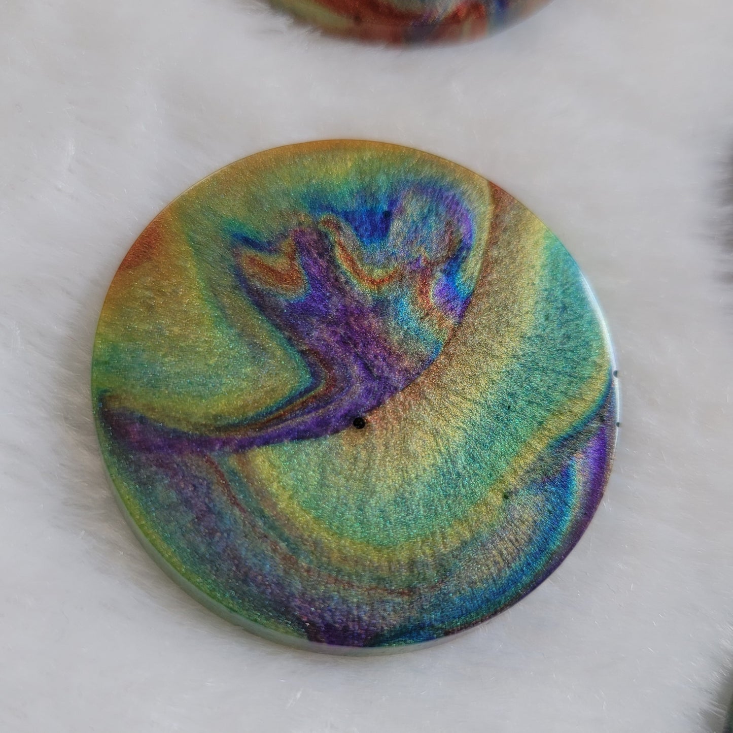 Round epoxy resin piece with colorful shimmering psychedelic swirls.