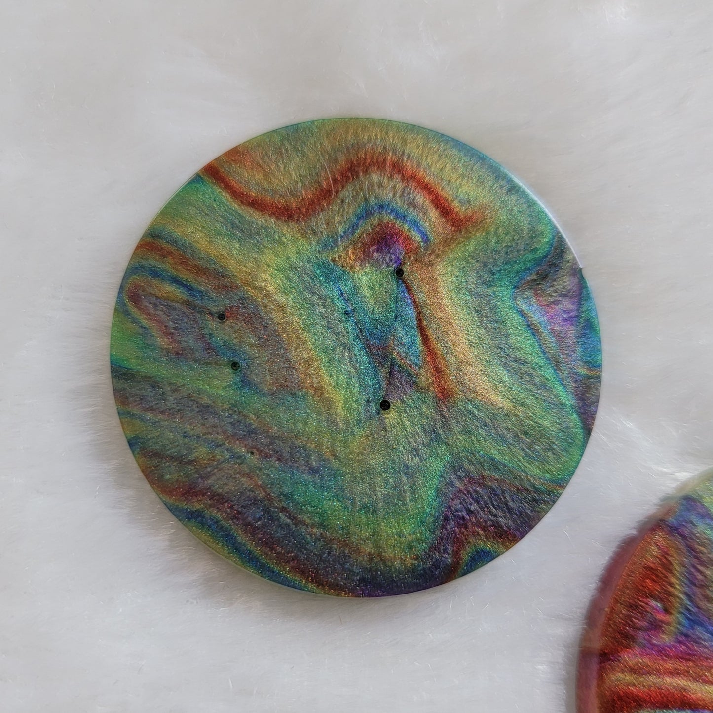 Round epoxy resin piece with colorful shimmering psychedelic swirls.