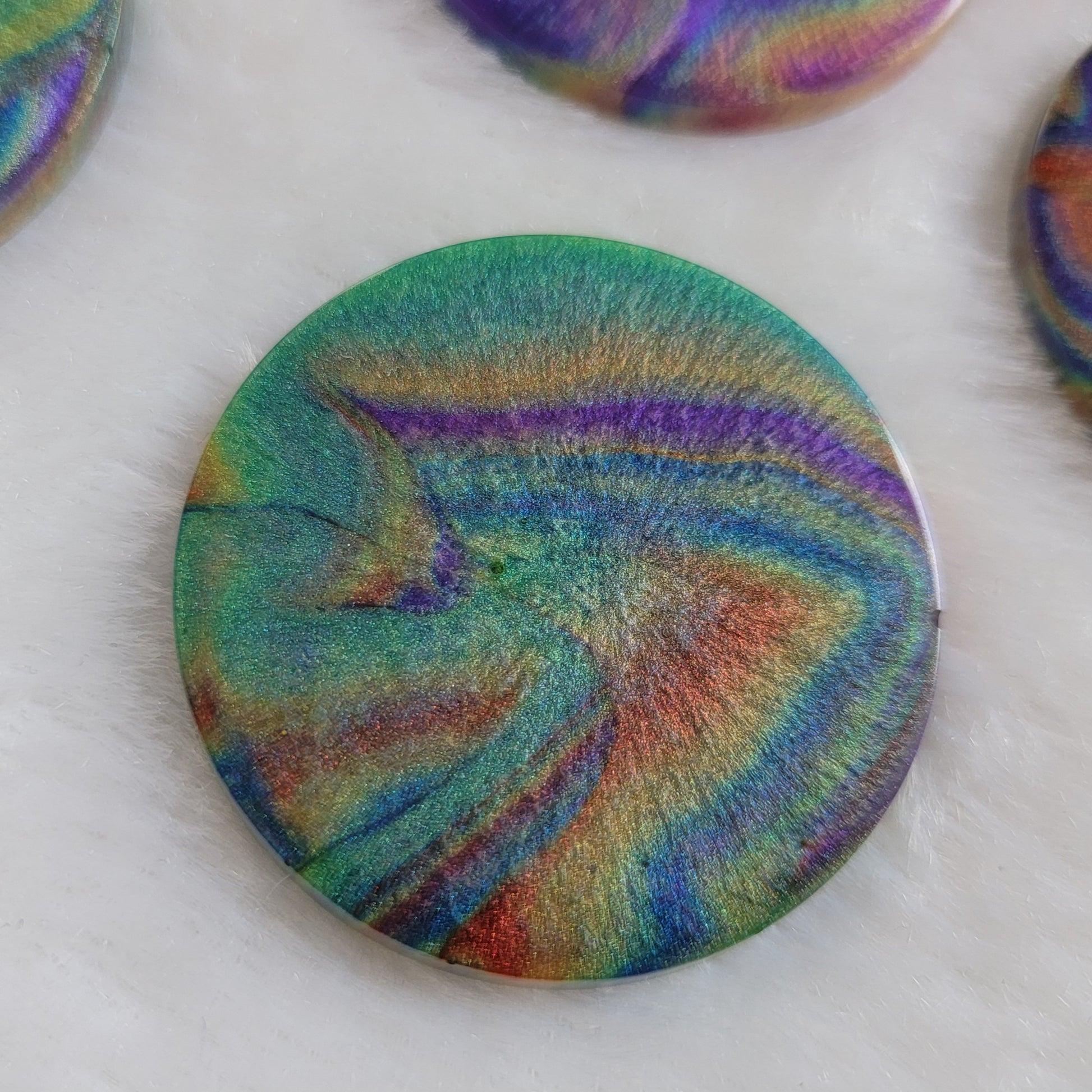 Round epoxy resin piece with colorful shimmering psychedelic swirls.