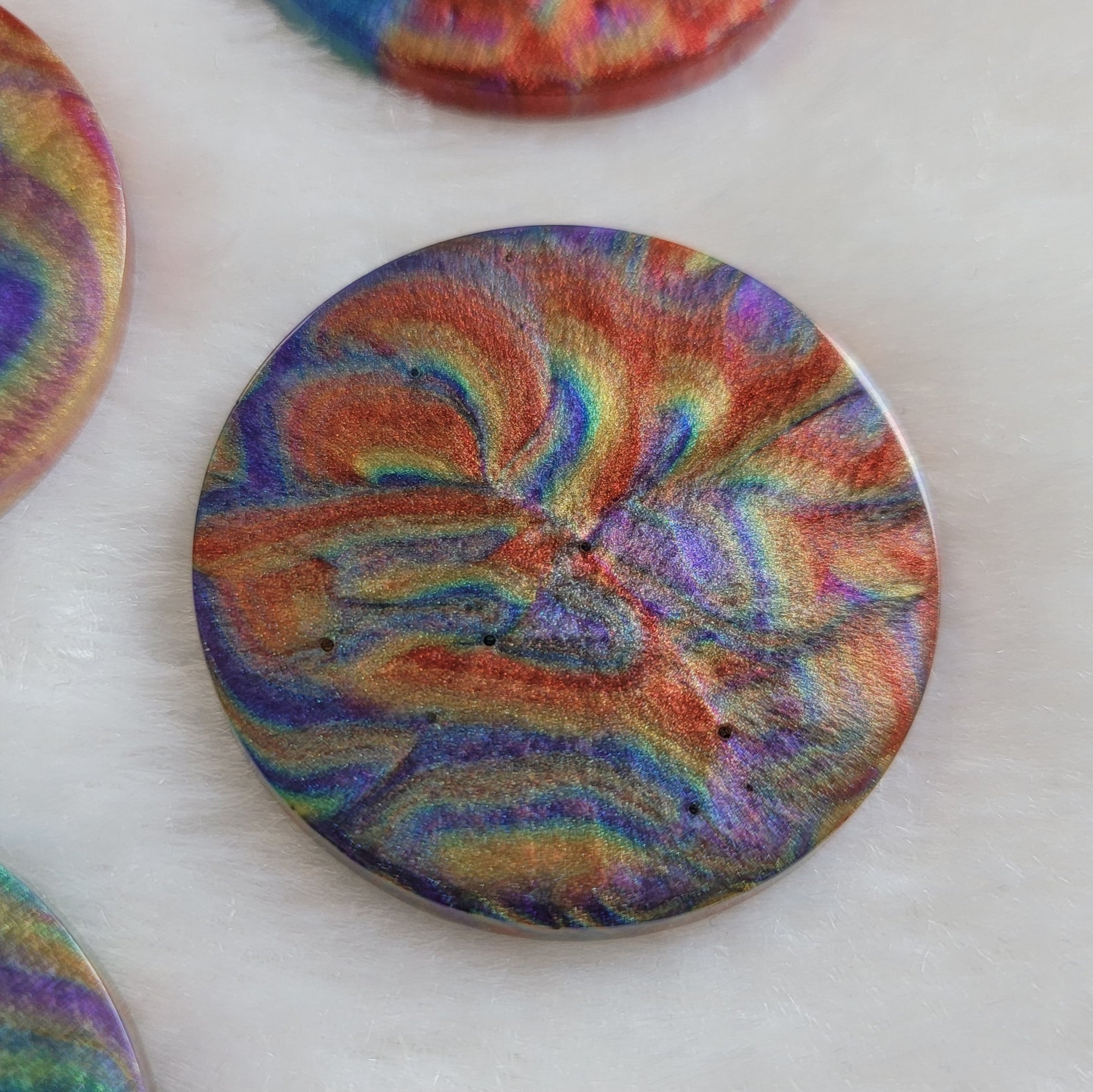 Round epoxy resin piece with colorful shimmering psychedelic swirls.